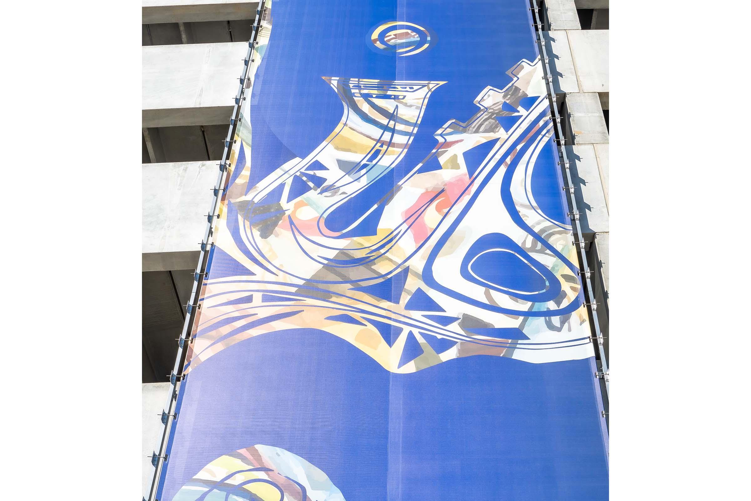 A colorful abstract design featuring flowing shapes and patterns, set against a blue background. The artwork appears on a tall banner, highlighting vibrant colors and an artistic composition. The overall aesthetic suggests a modern and dynamic visual identity.