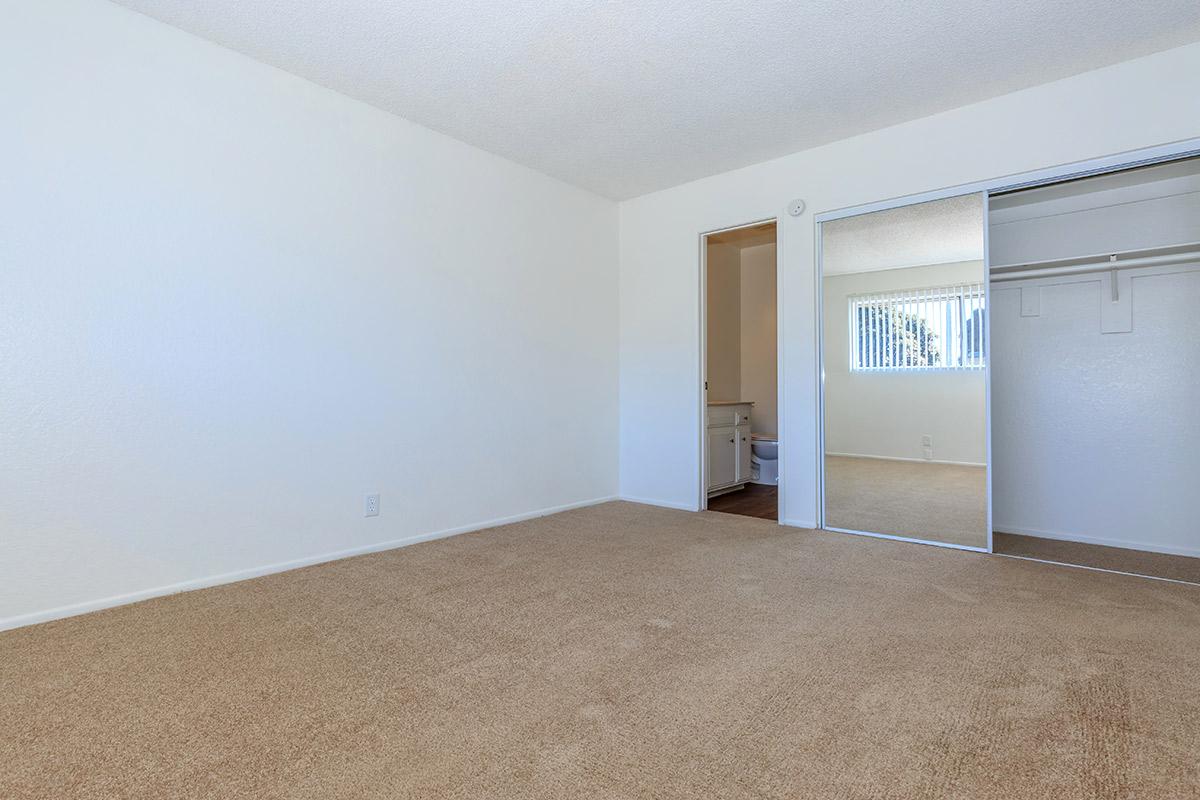 Carpeted bedroom with sliding mirror glass closet doors