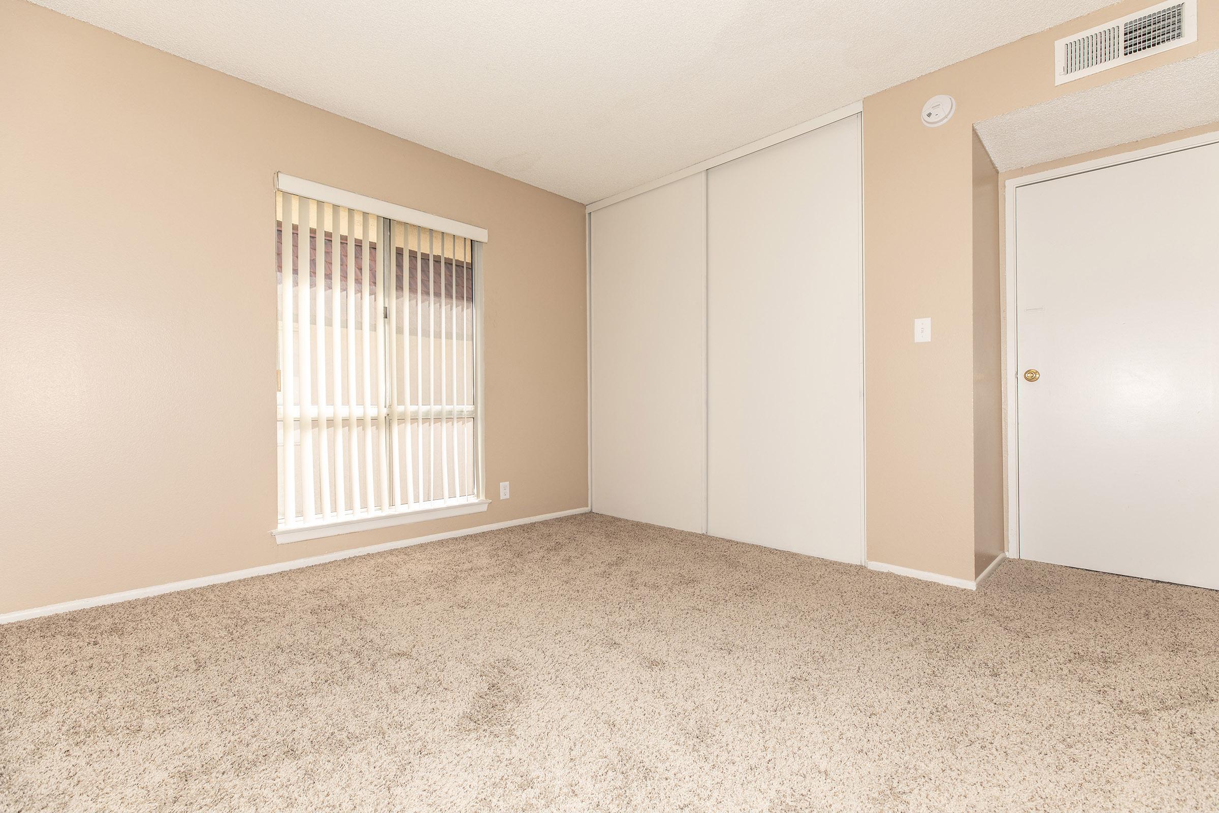Vacant carpeted bedroom with closed sliding closet doors
