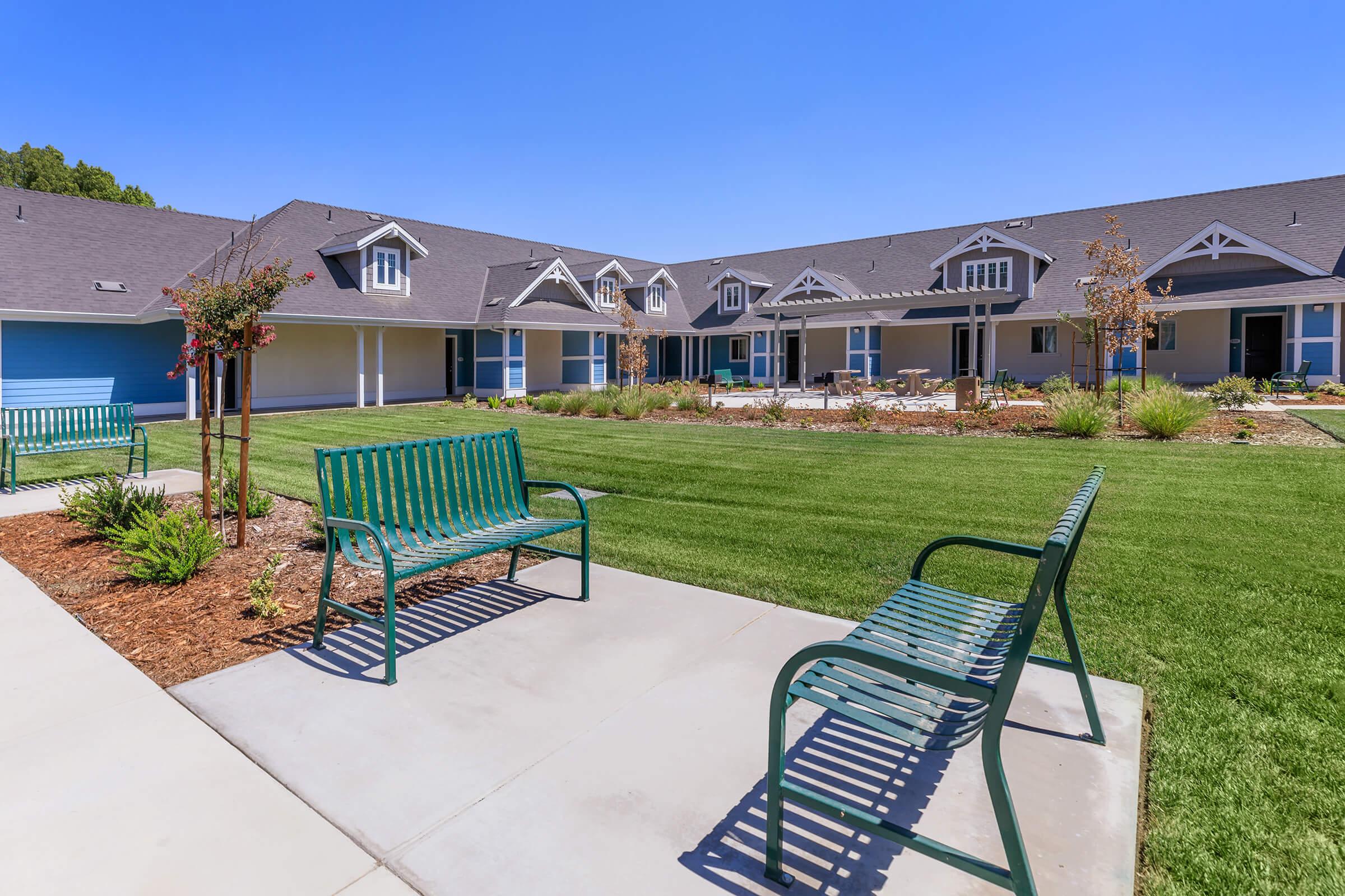 a couple of lawn chairs sitting on a bench in front of a house