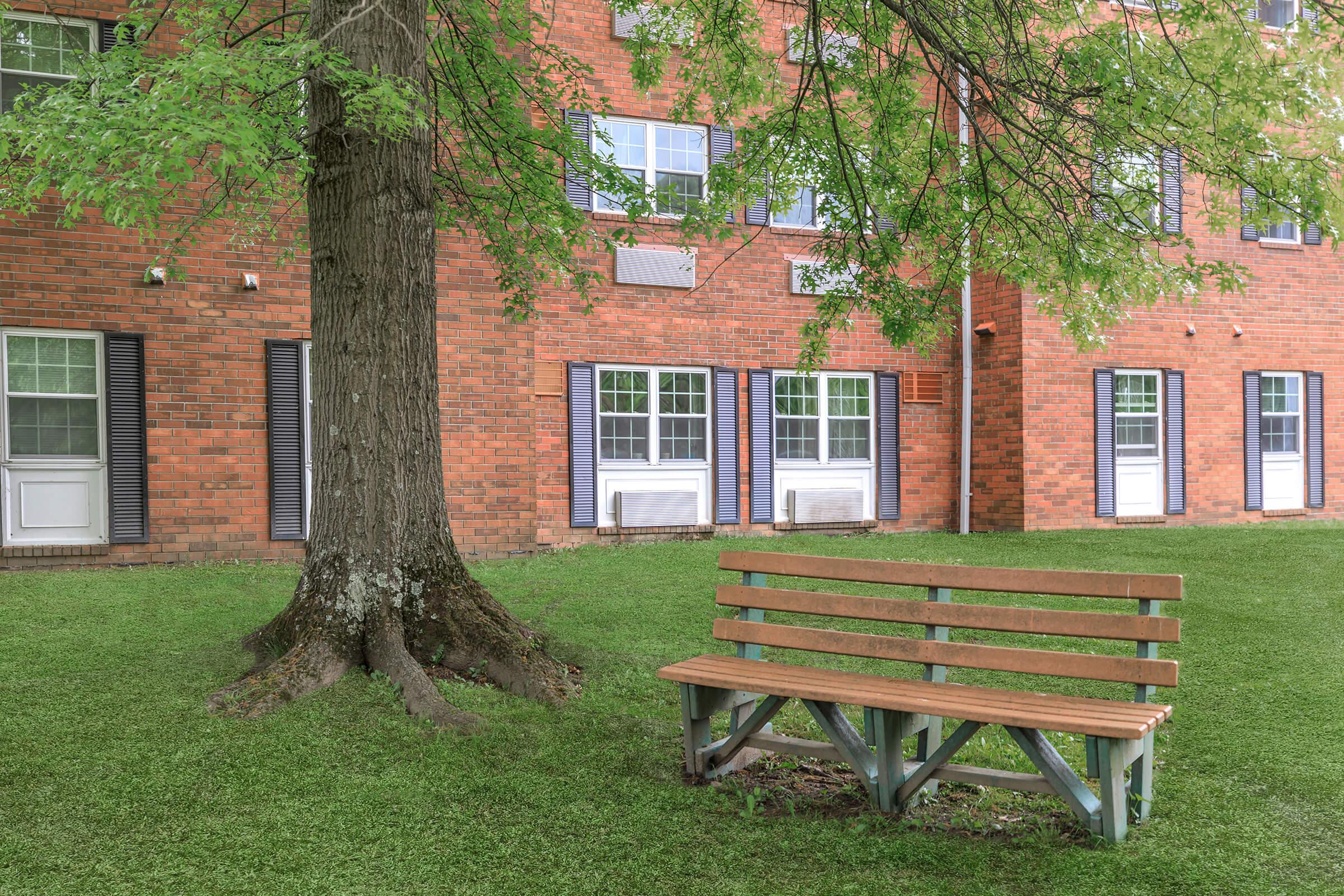 an empty park bench sitting in front of a brick building