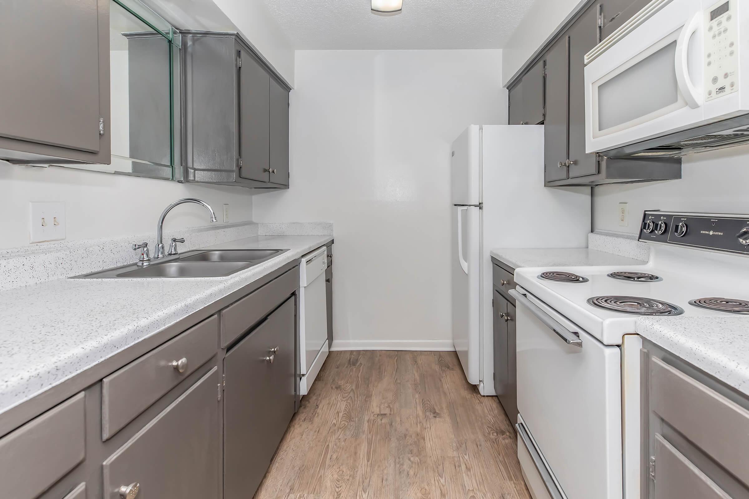 a kitchen with a stove a sink and a microwave oven above a refrigerator