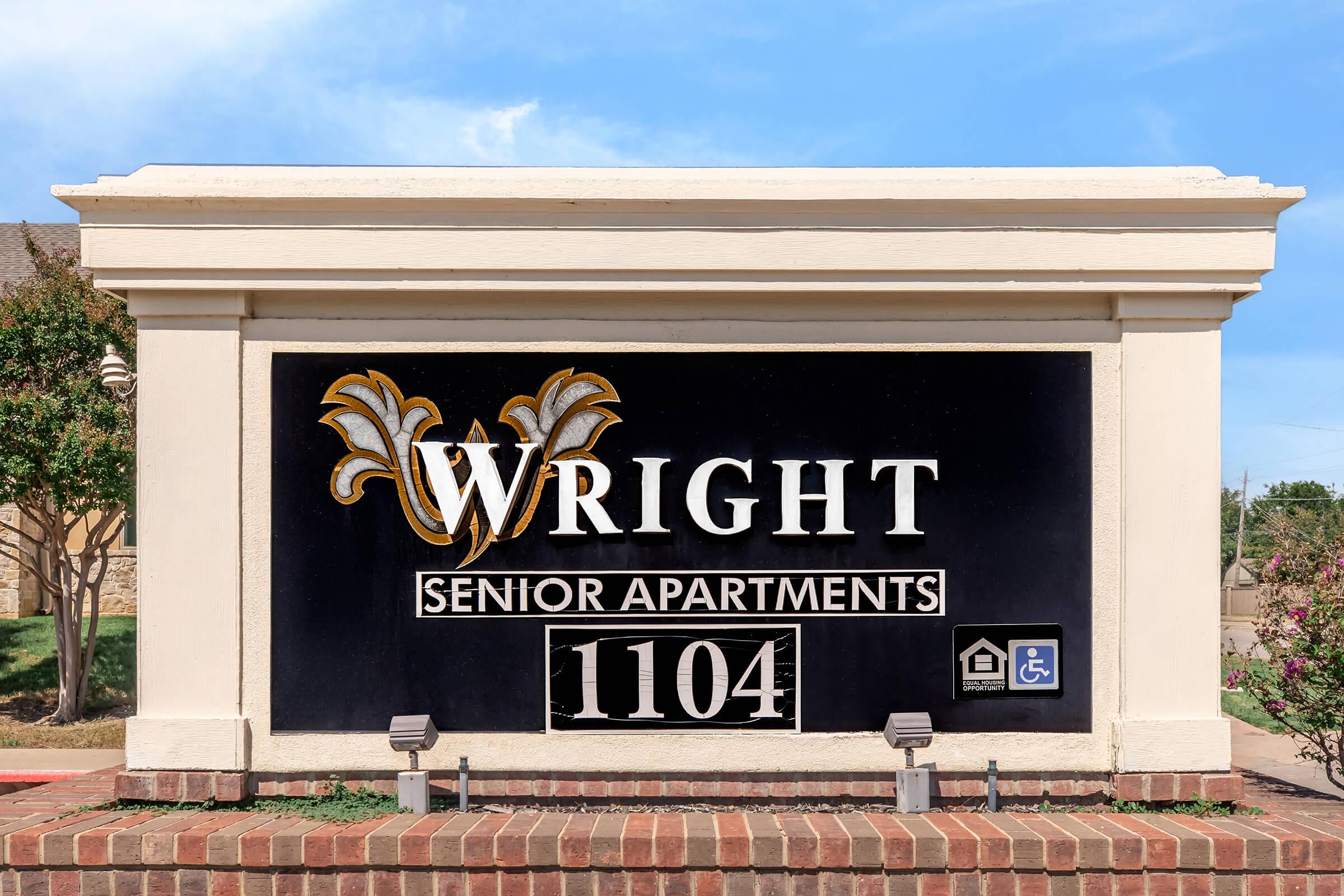 Sign for Wright Senior Apartments with the address 1104. The sign features decorative elements and includes accessible symbols, suggesting it is a residence tailored for seniors.