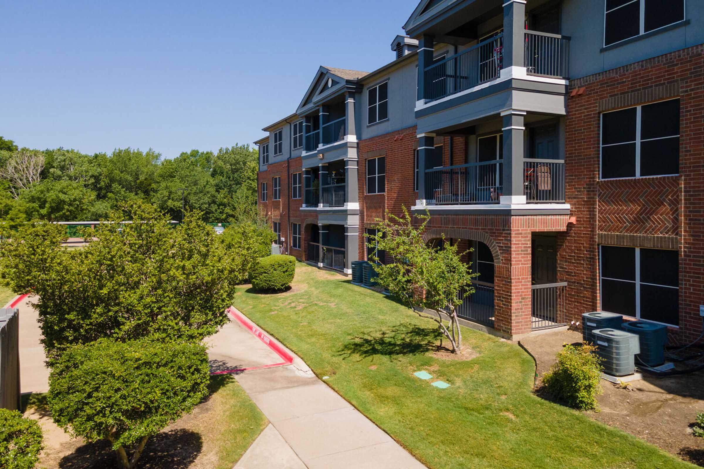 View of an apartment complex featuring two buildings with brick and gray siding.
