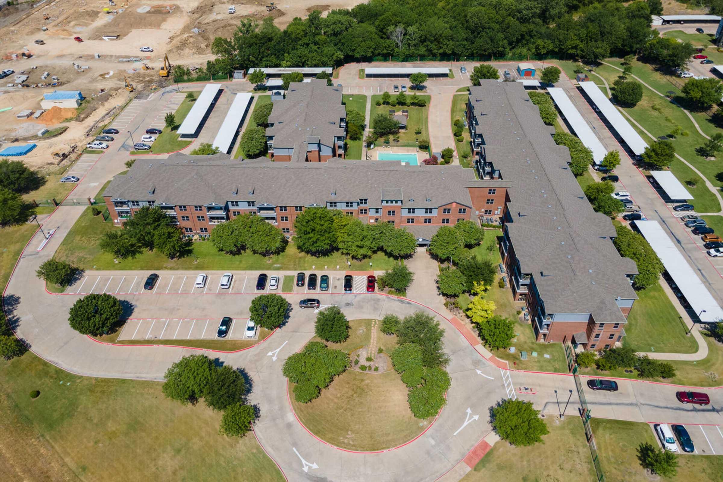 Aerial view of a residential complex featuring multiple two-story buildings arranged around a circular driveway.