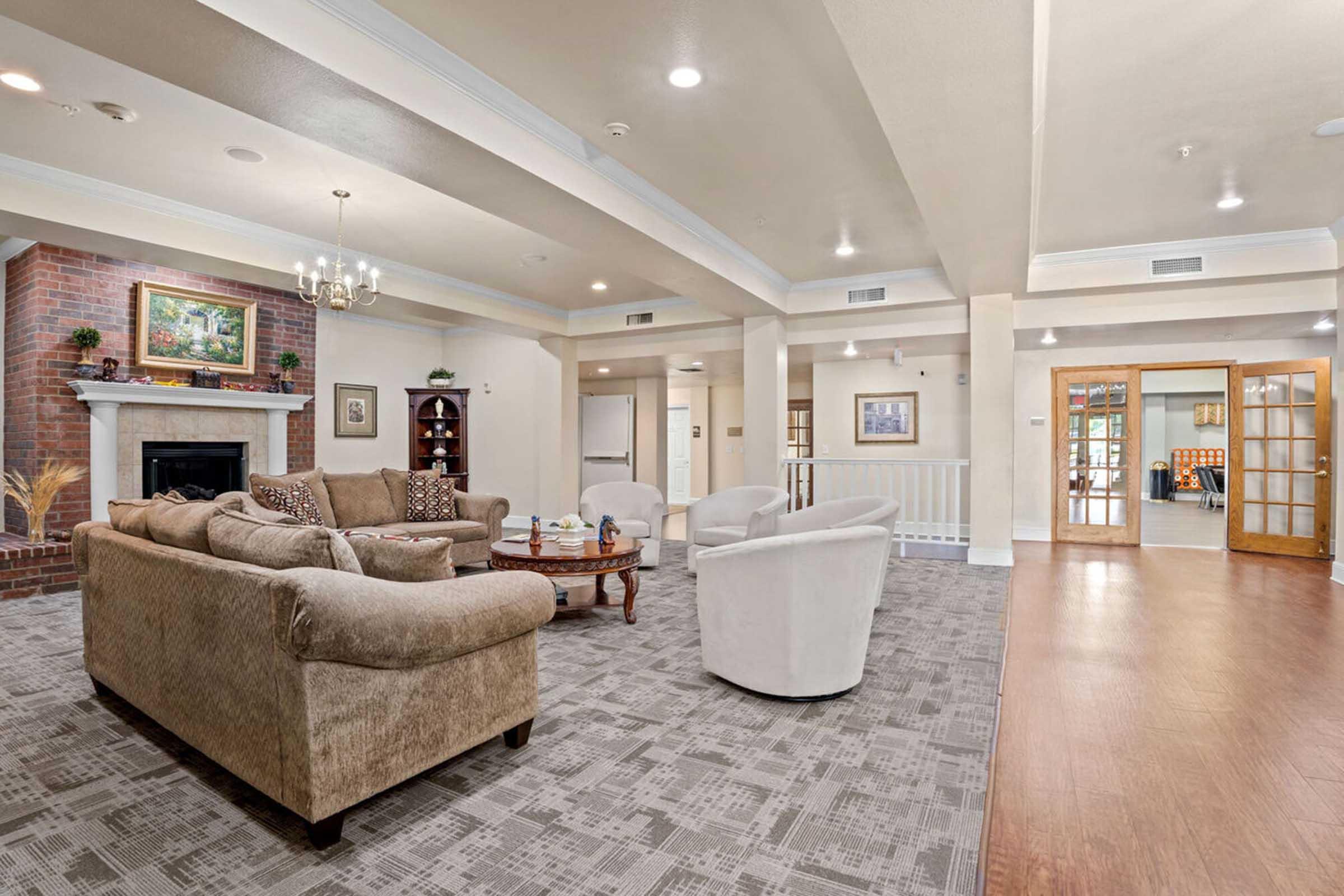 A spacious and well-lit living room featuring a cozy seating arrangement with a large beige sofa and two white armchairs.