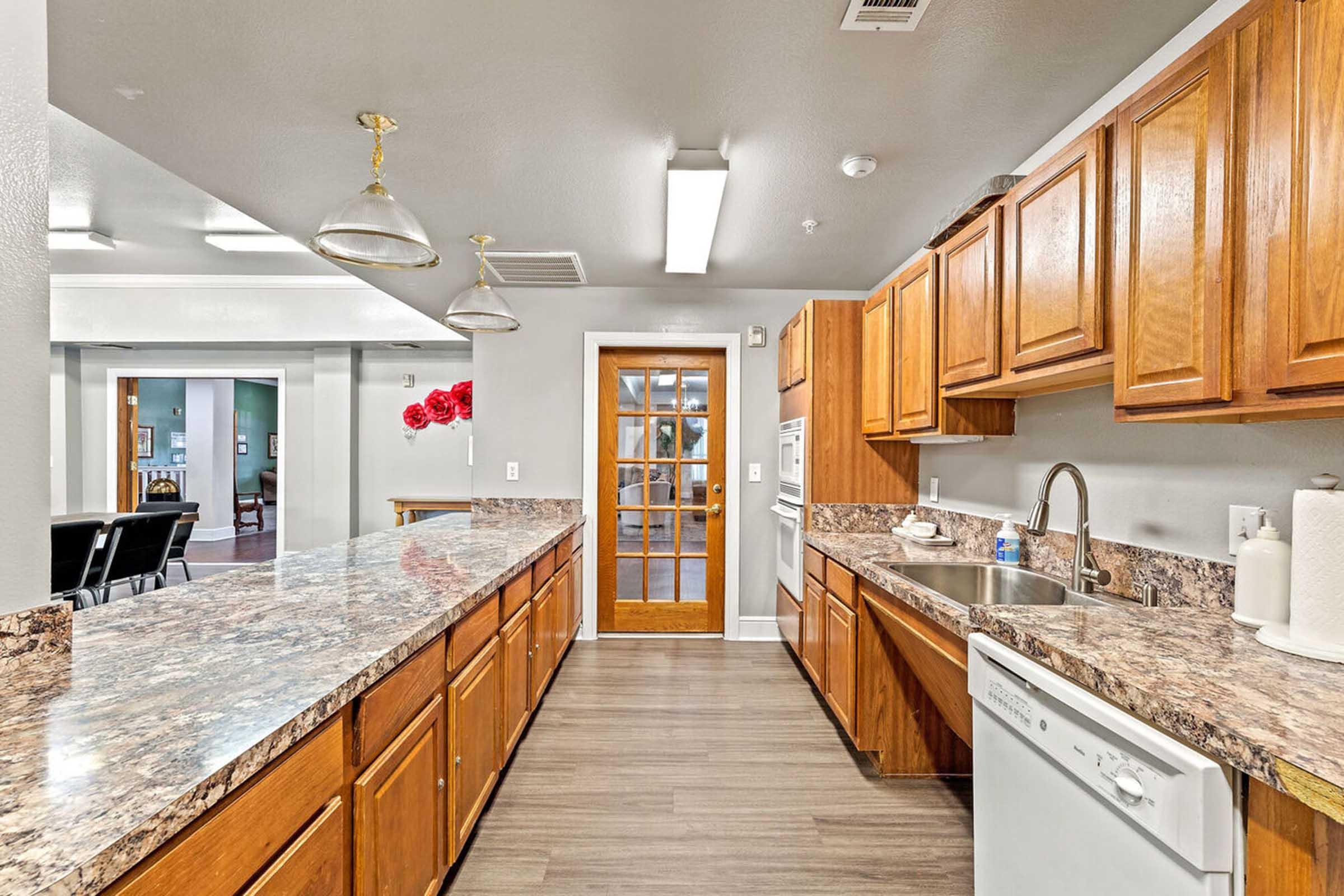 A modern kitchen featuring wooden cabinets, a granite countertop, and white appliances.
