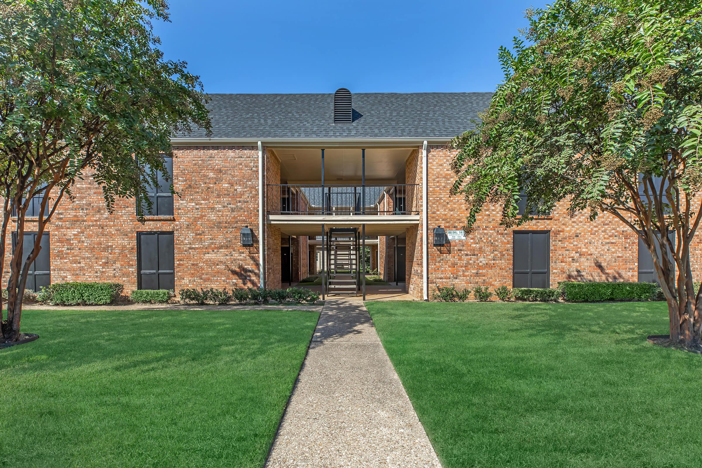 a large brick building with grass in front of a house