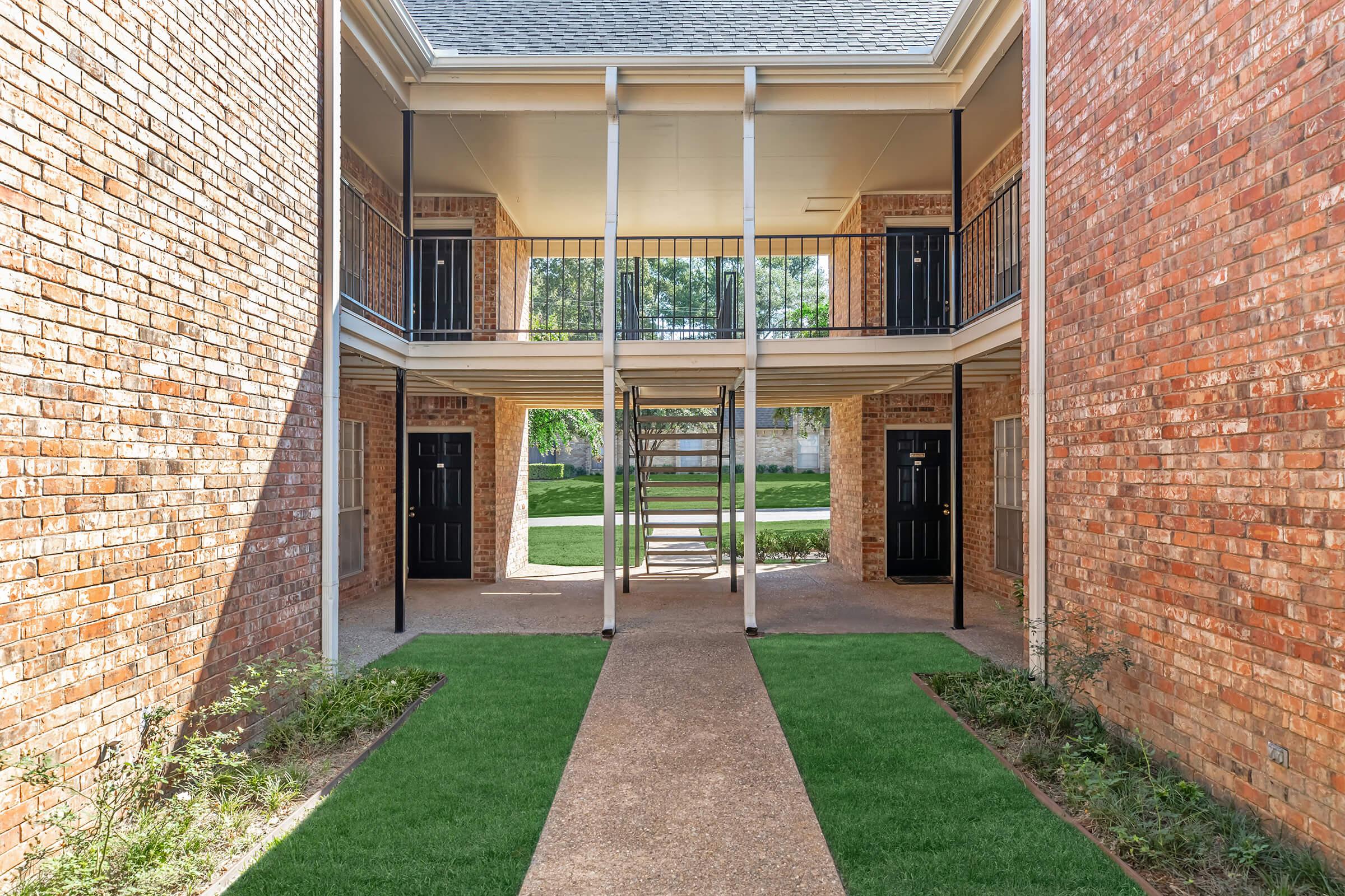 a stone building that has grass in front of a brick wall