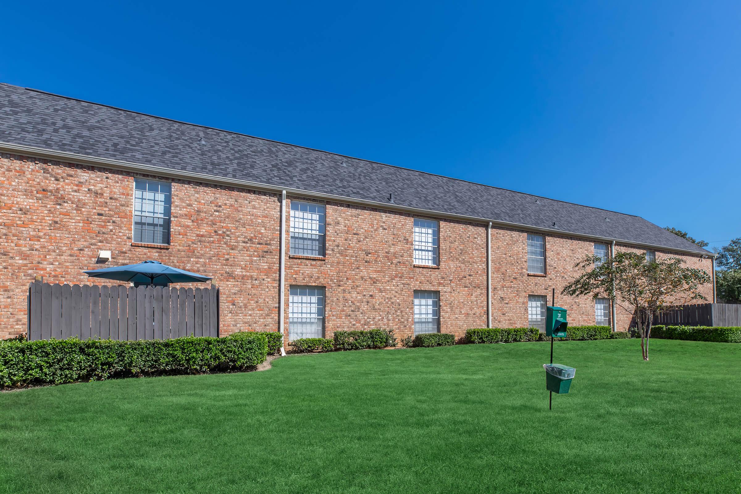 a large lawn in front of a brick building