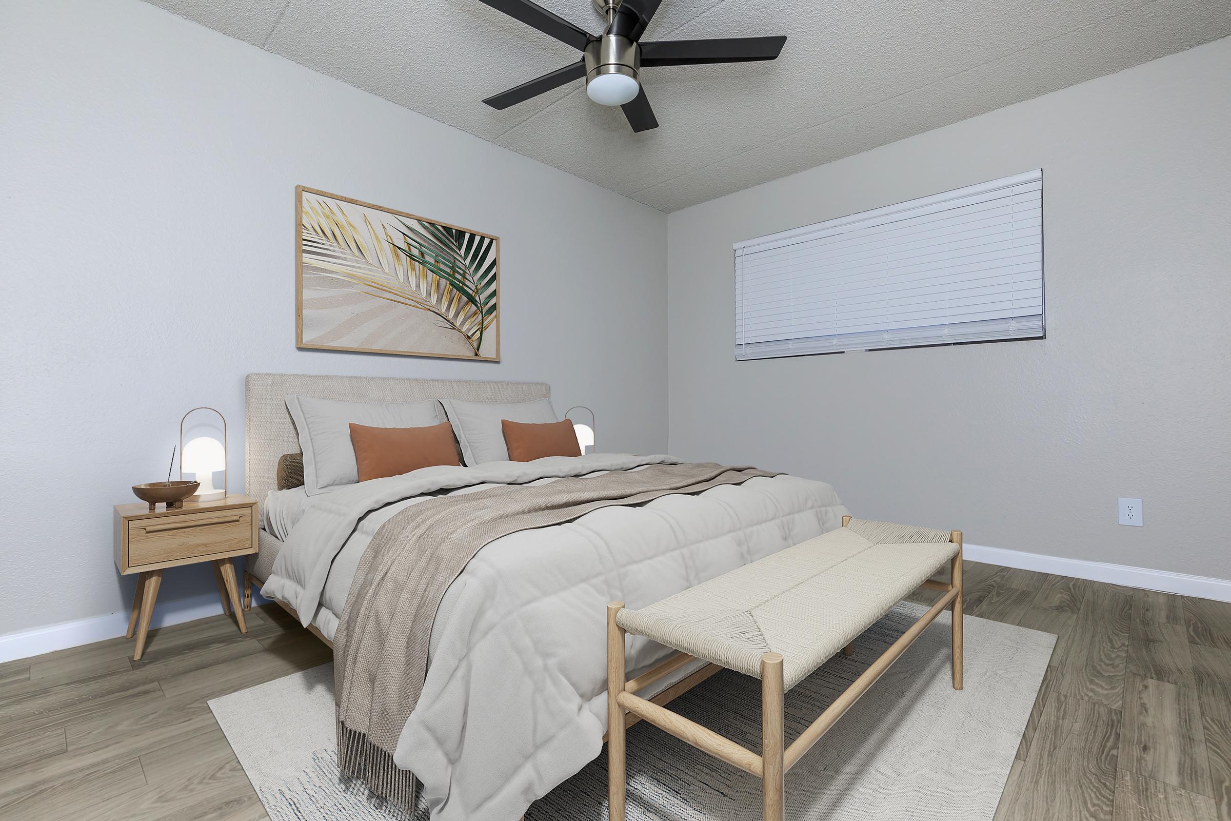 A modern bedroom featuring a queen-sized bed with beige linens and two decorative orange pillows. A wooden nightstand holds stylish lamps on either side. A light-colored bench sits at the foot of the bed, and a framed piece of wall art with botanical elements is displayed above the headboard. Natural light enters through a window with blinds.