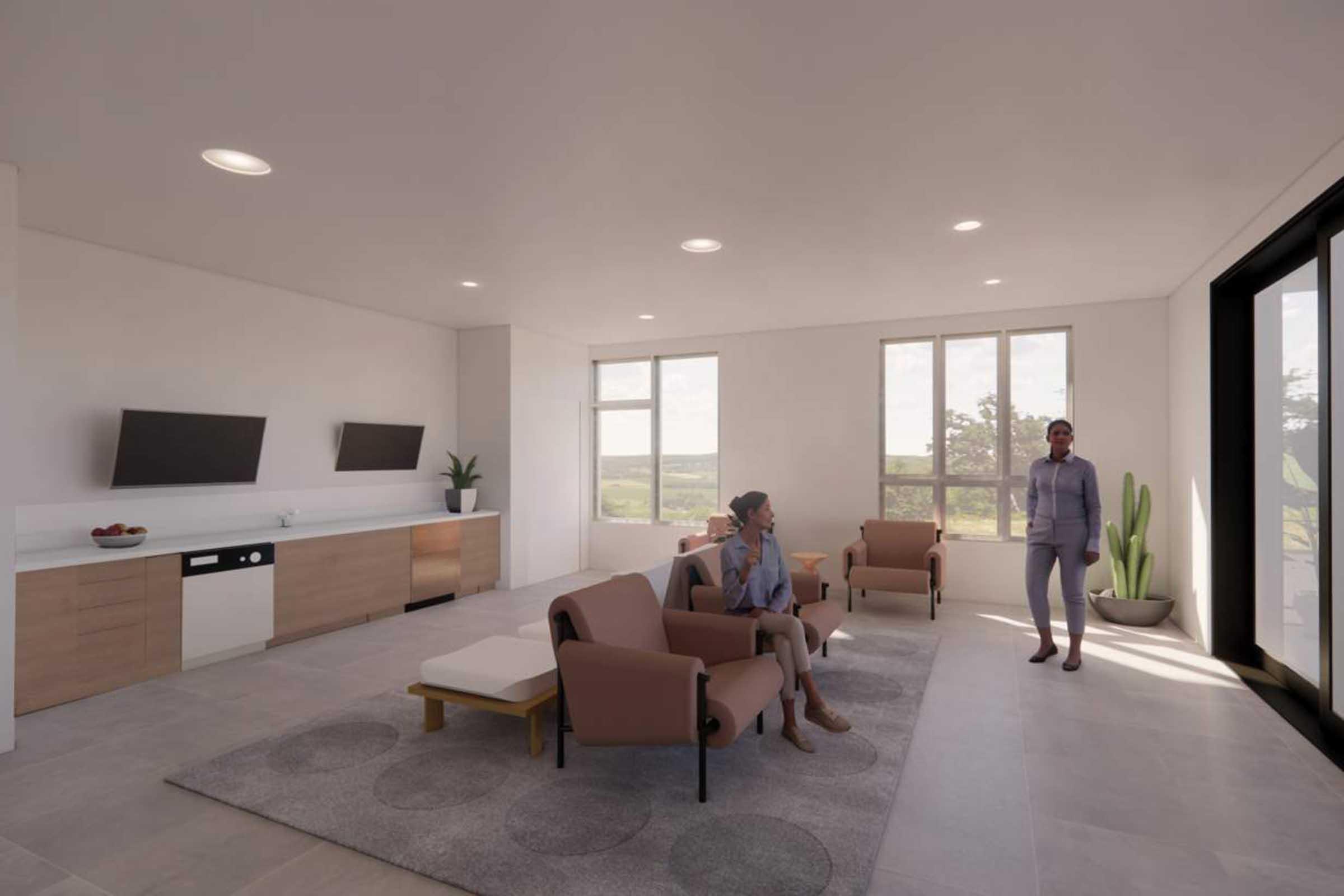 A modern living room with large windows and natural light. Two people sit on a beige sofa, engaged in conversation. A third person stands near the doorway. The room features wooden furniture, two wall-mounted TVs, and a potted plant, creating a spacious and inviting atmosphere.