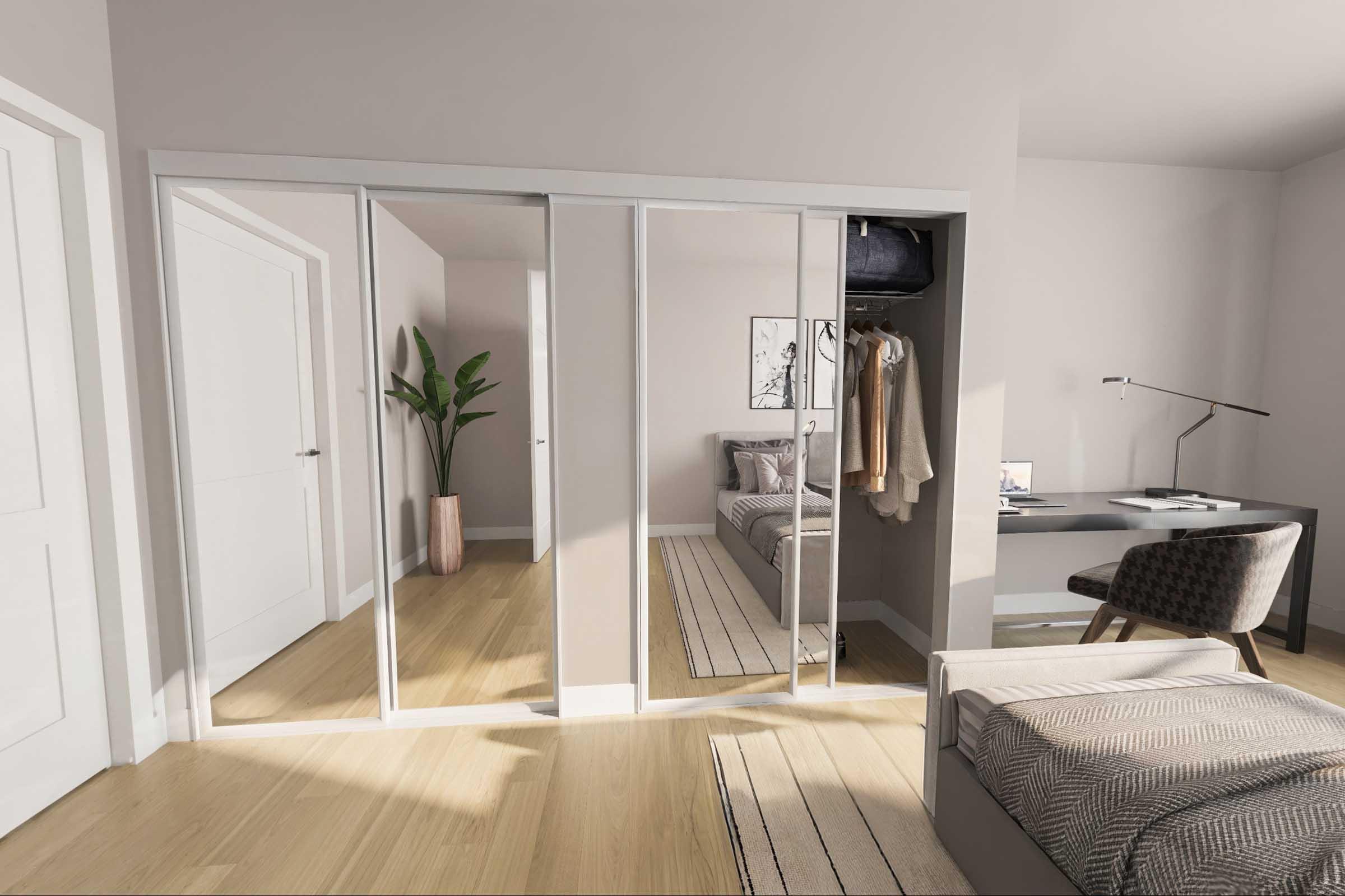 A modern bedroom featuring a mirrored wardrobe, a neatly made bed with a patterned throw, a small desk with a lamp, and a comfortable chair. A plant is placed in a corner, adding a touch of greenery. Light-colored walls and wooden flooring enhance the spacious feel of the room.