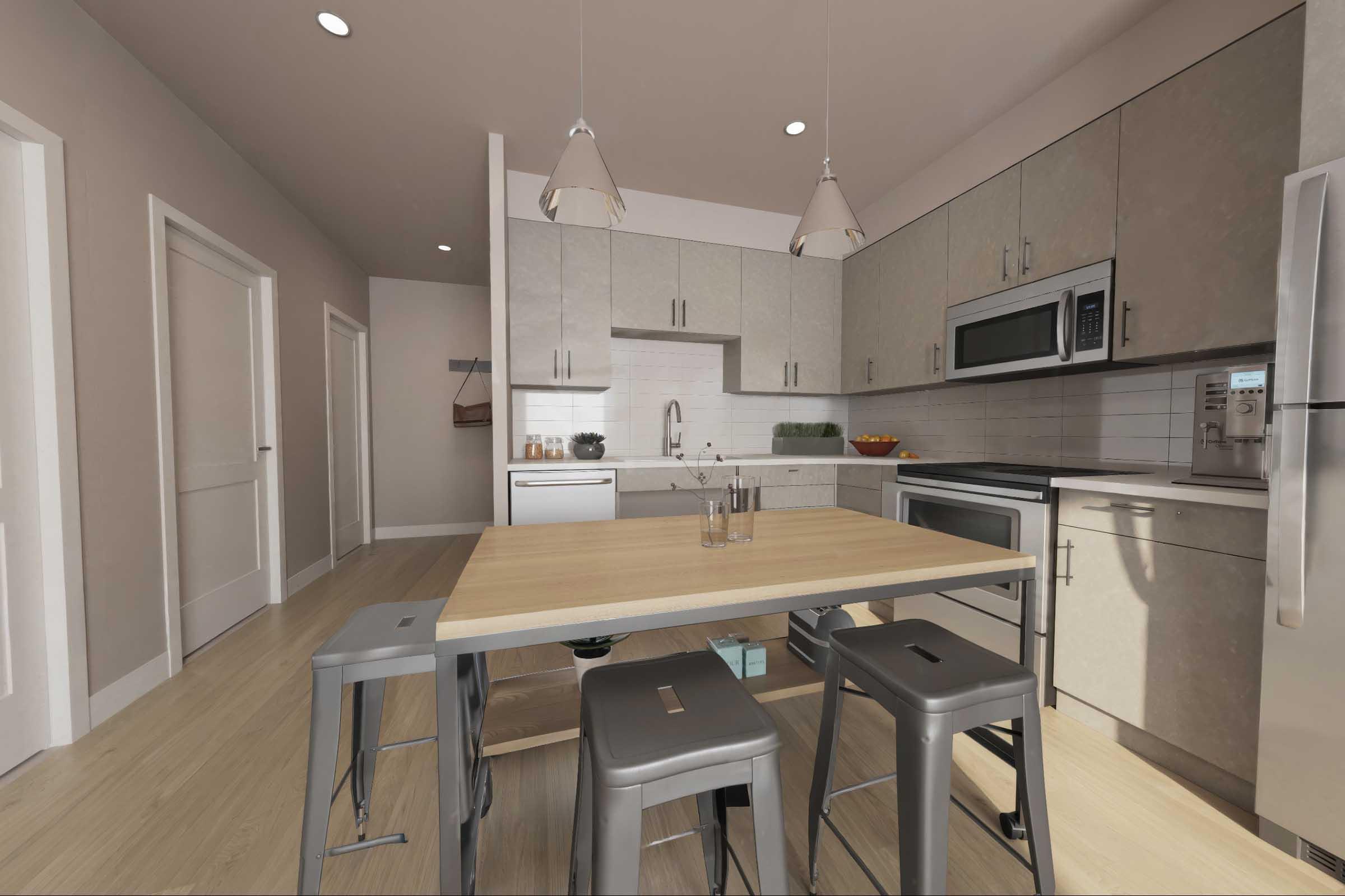 A modern, spacious kitchen featuring sleek cabinets, stainless steel appliances, and a large wooden dining table with metal stools. The room is well-lit, showcasing an open layout with a door to the left, a window above the sink, and decorative fruit in a bowl on the counter.