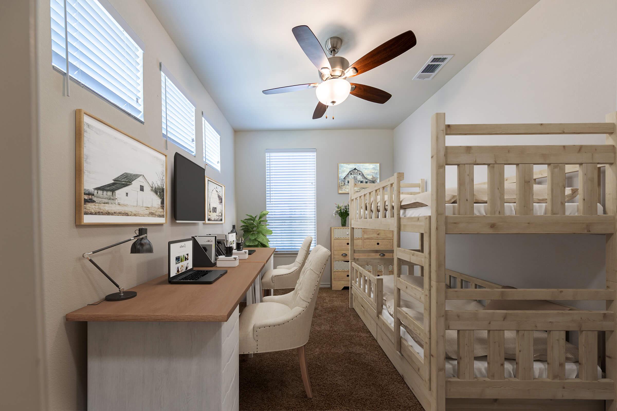 A cozy room featuring a bunk bed, a desk with a computer setup, and a comfortable chair. The walls are adorned with framed artworks, and sunlight filters through the horizontal blinds. A ceiling fan adds to the inviting atmosphere, while a plant brings a touch of nature to the space.