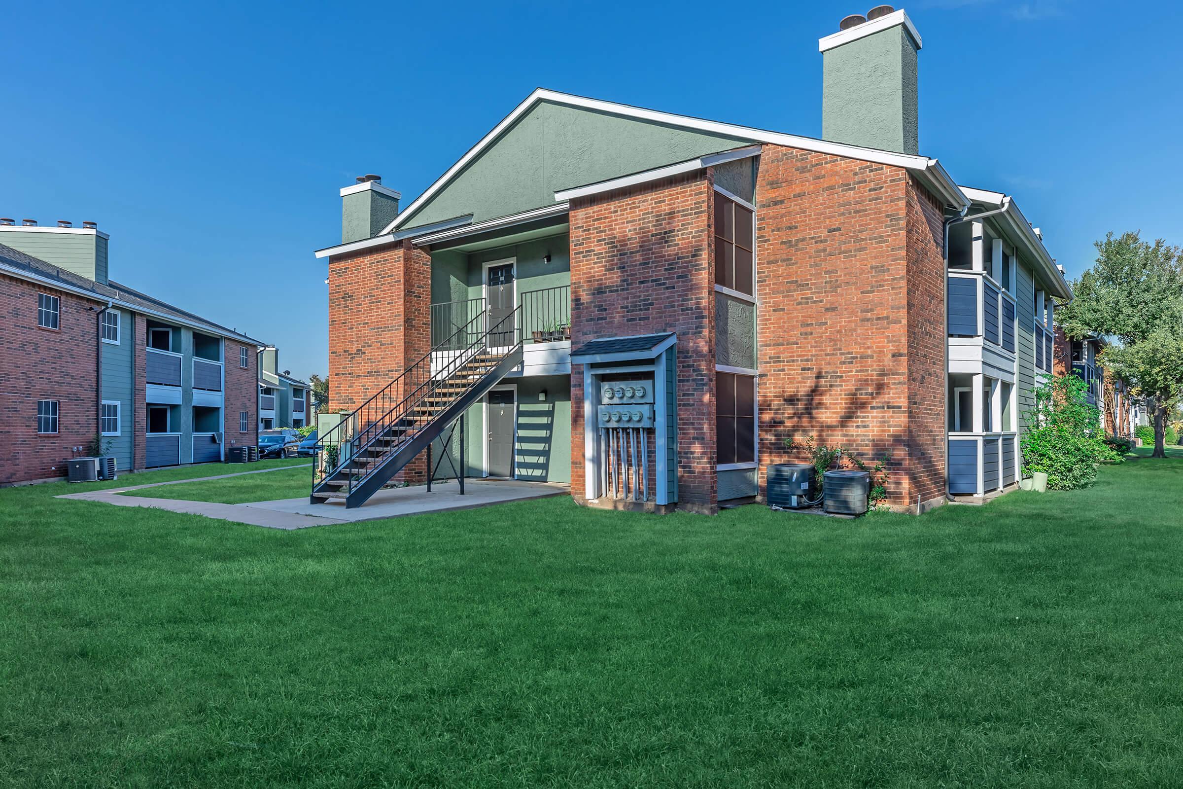 a large brick building with grass in front of a house