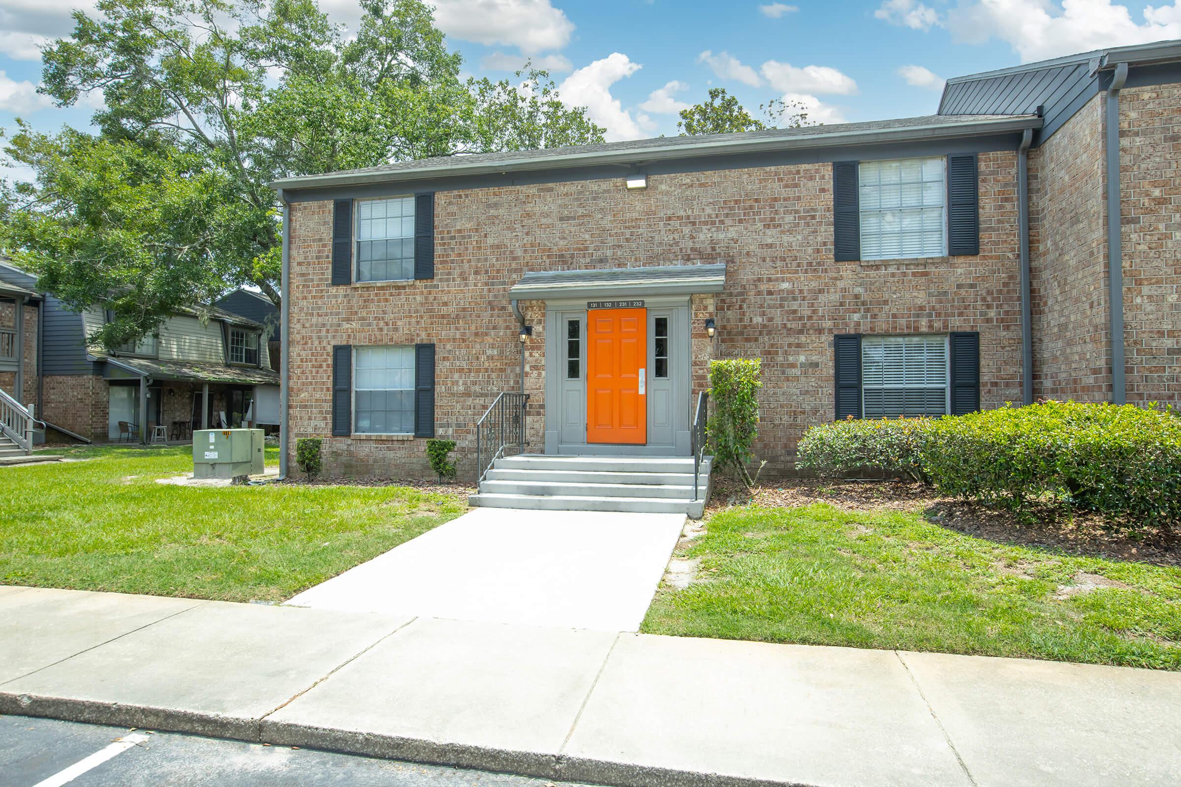 a large brick building with grass in front of a house