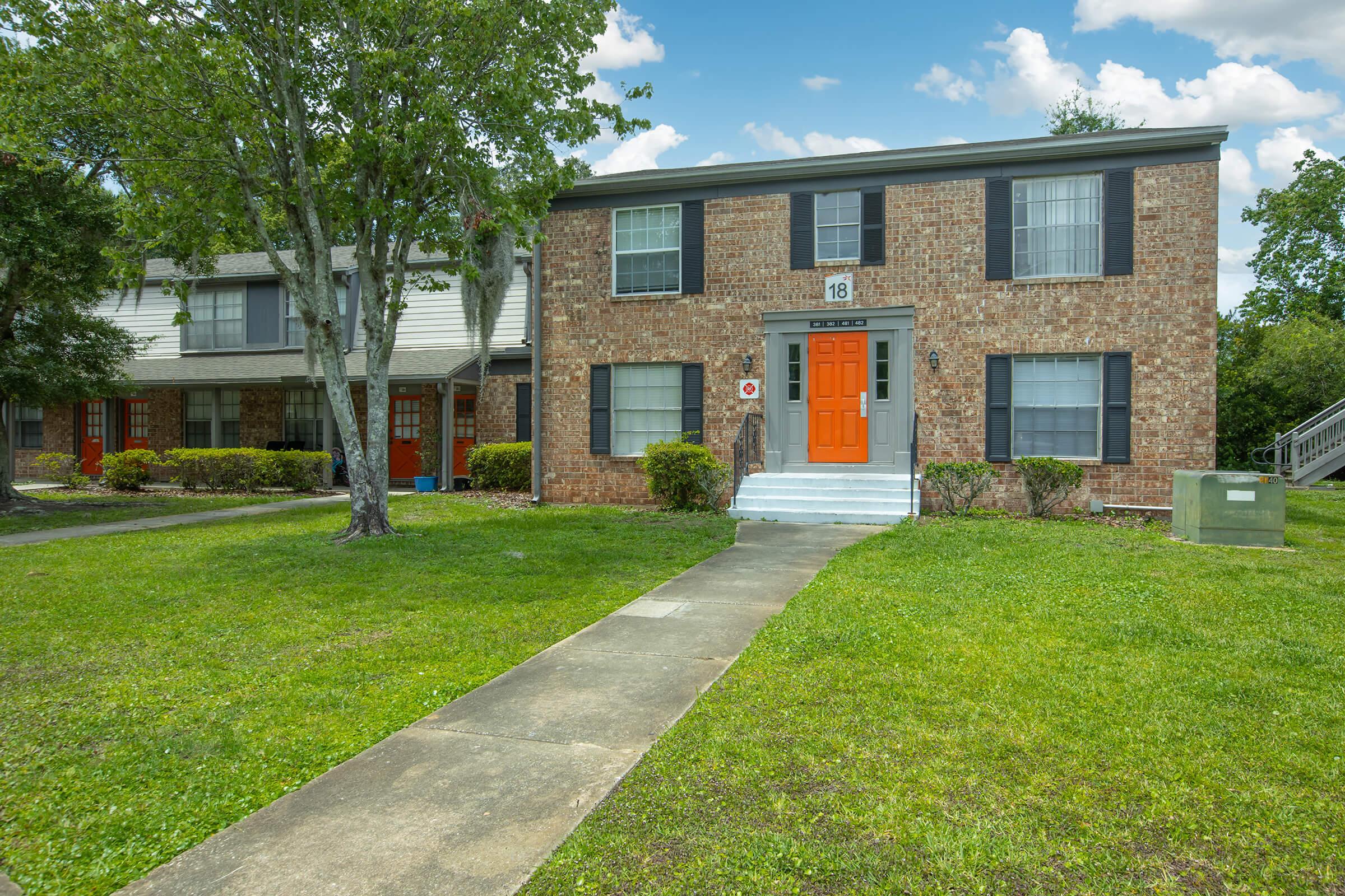 a large brick building with grass in front of a house