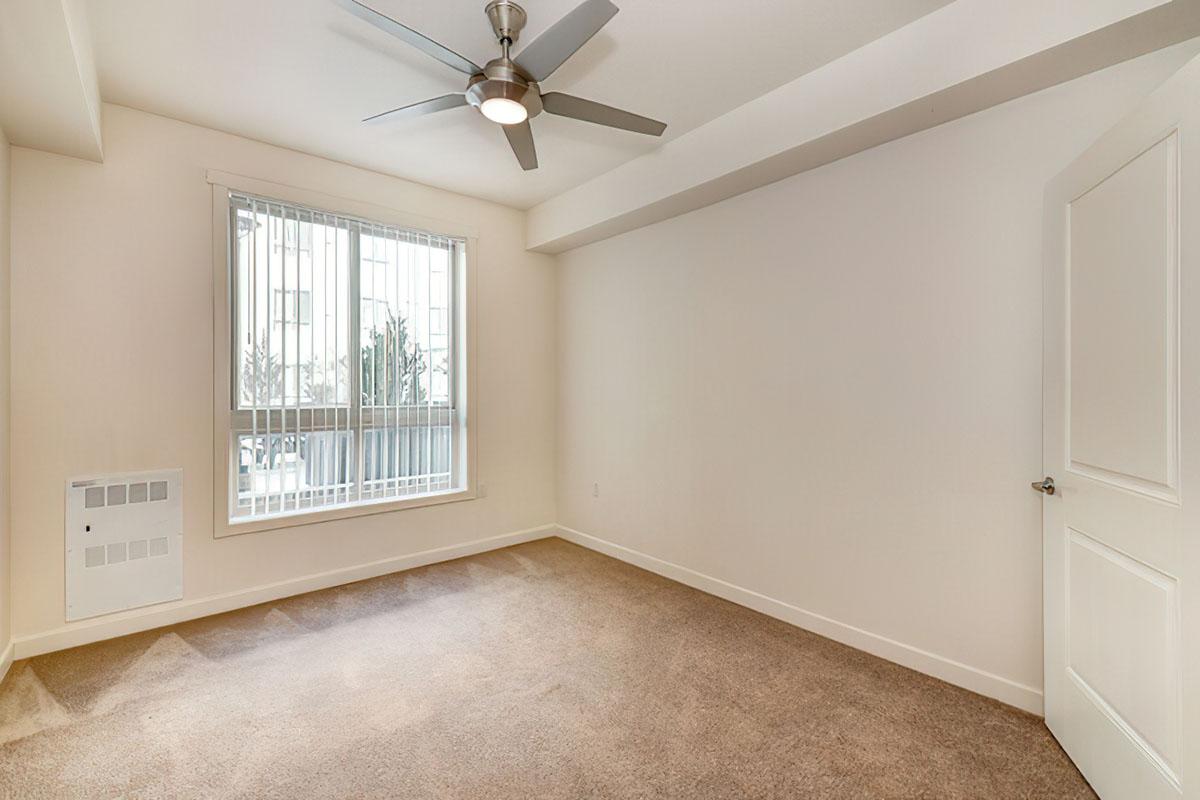 A spacious, empty room featuring beige carpet and light-colored walls.