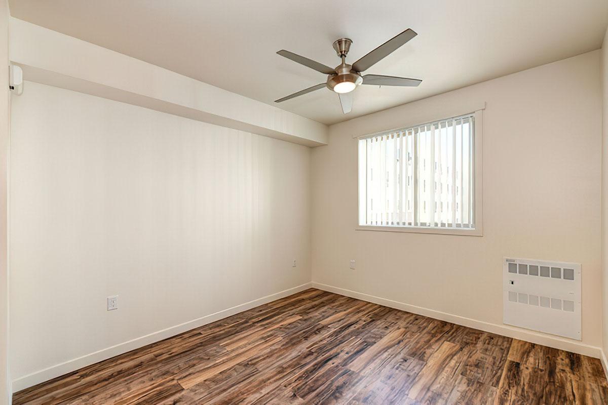 The generated text is: Empty room with light-colored walls and wood-like laminate flooring.
