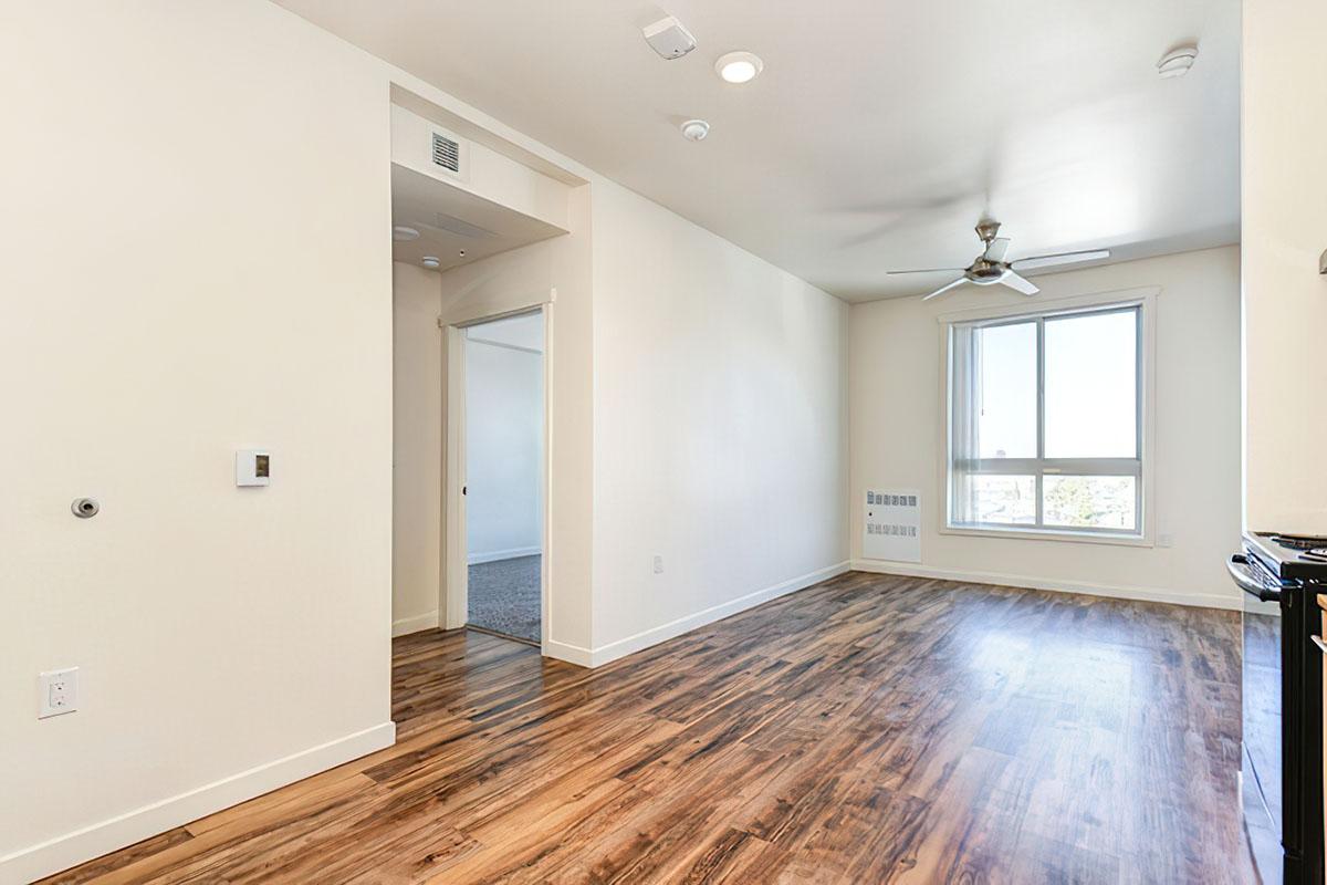 A bright, empty room featuring light-colored walls and a wooden floor.