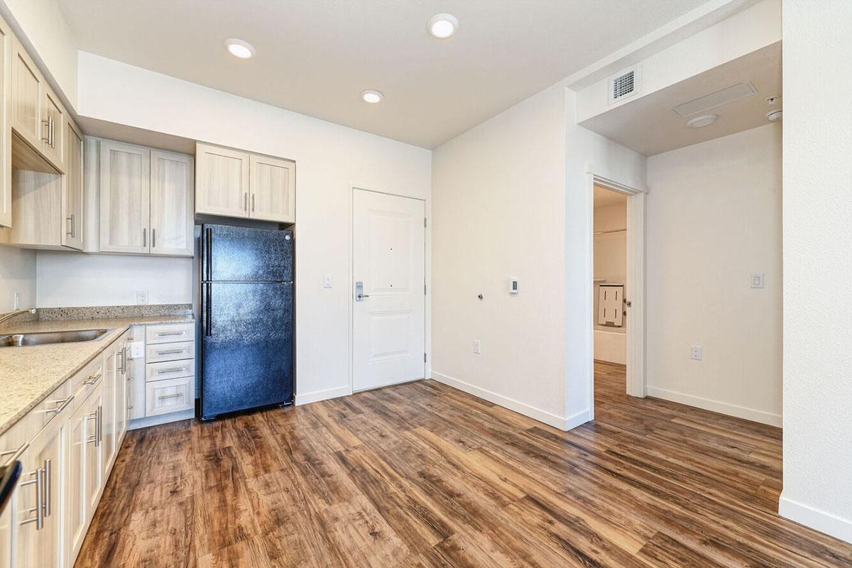 Modern kitchen with light wood cabinetry, granite countertops, and a black refrigerator.