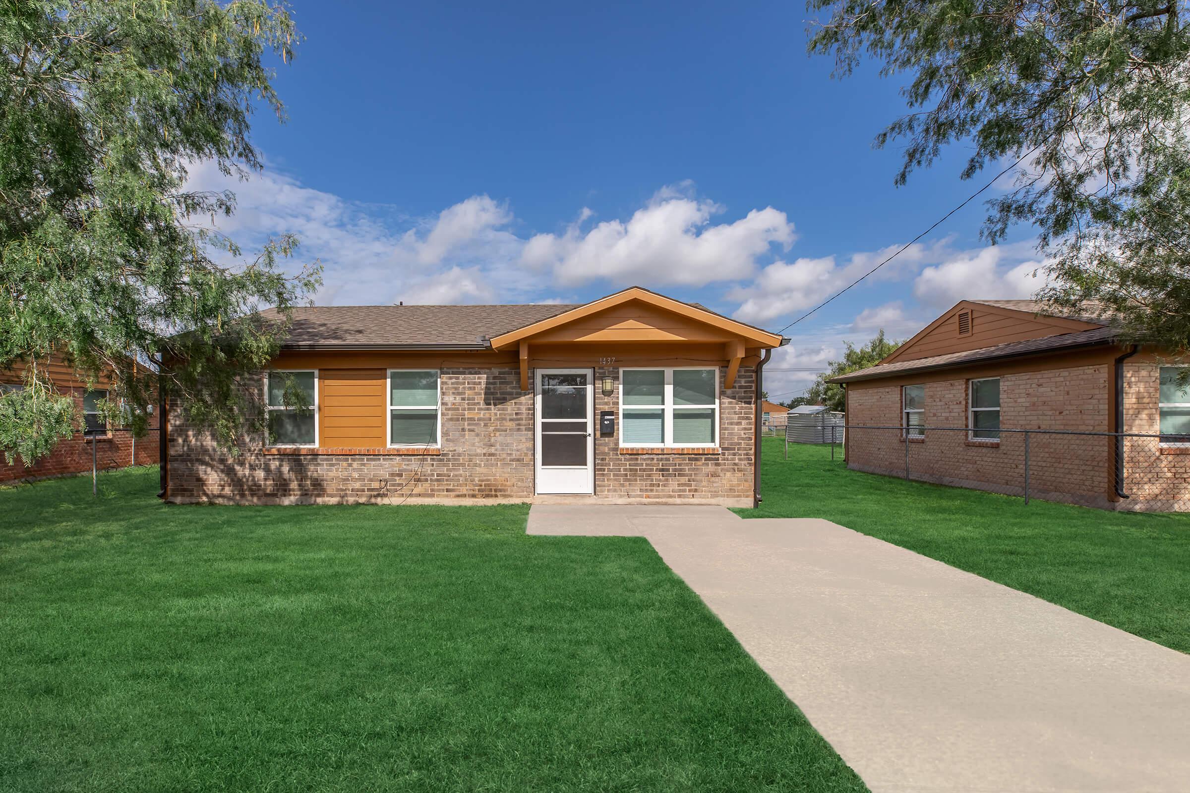 a house with a lawn in front of a brick building