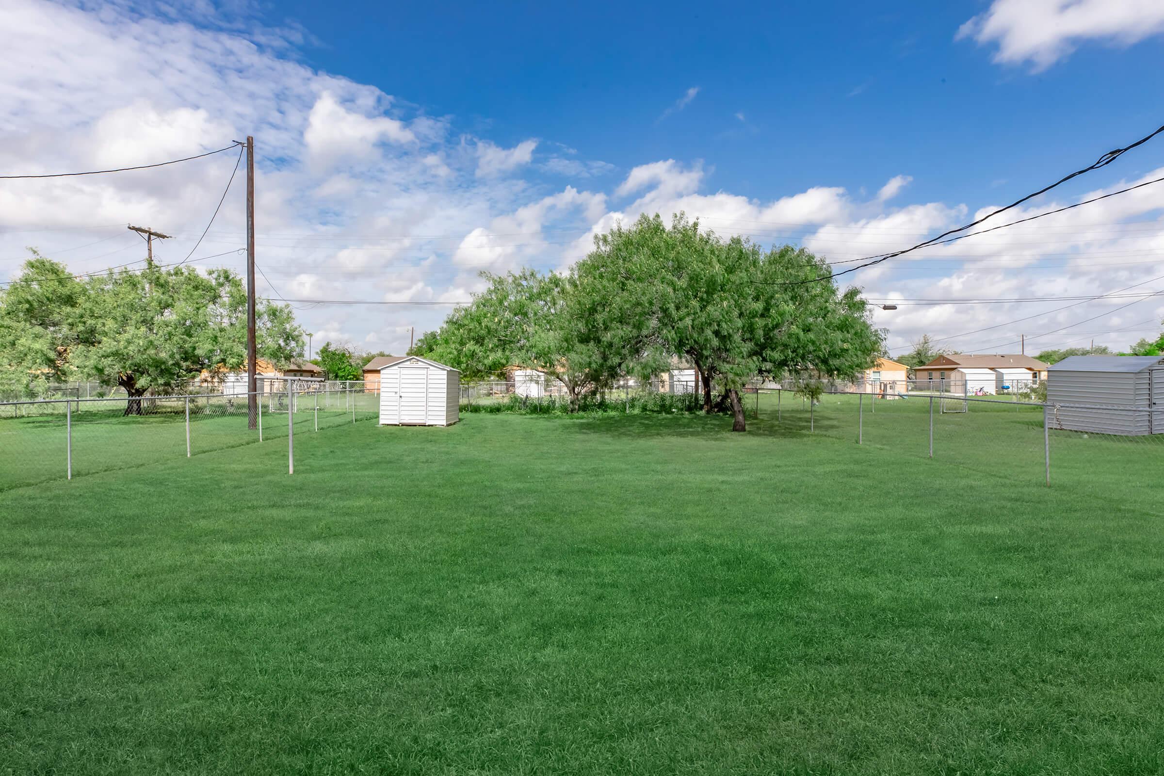 a large green field with trees in the background