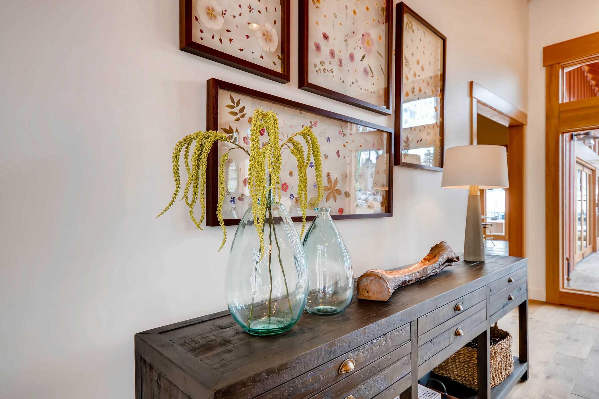 A side table adorned with two glass vases holding green plants, complemented by decorative wooden logs.