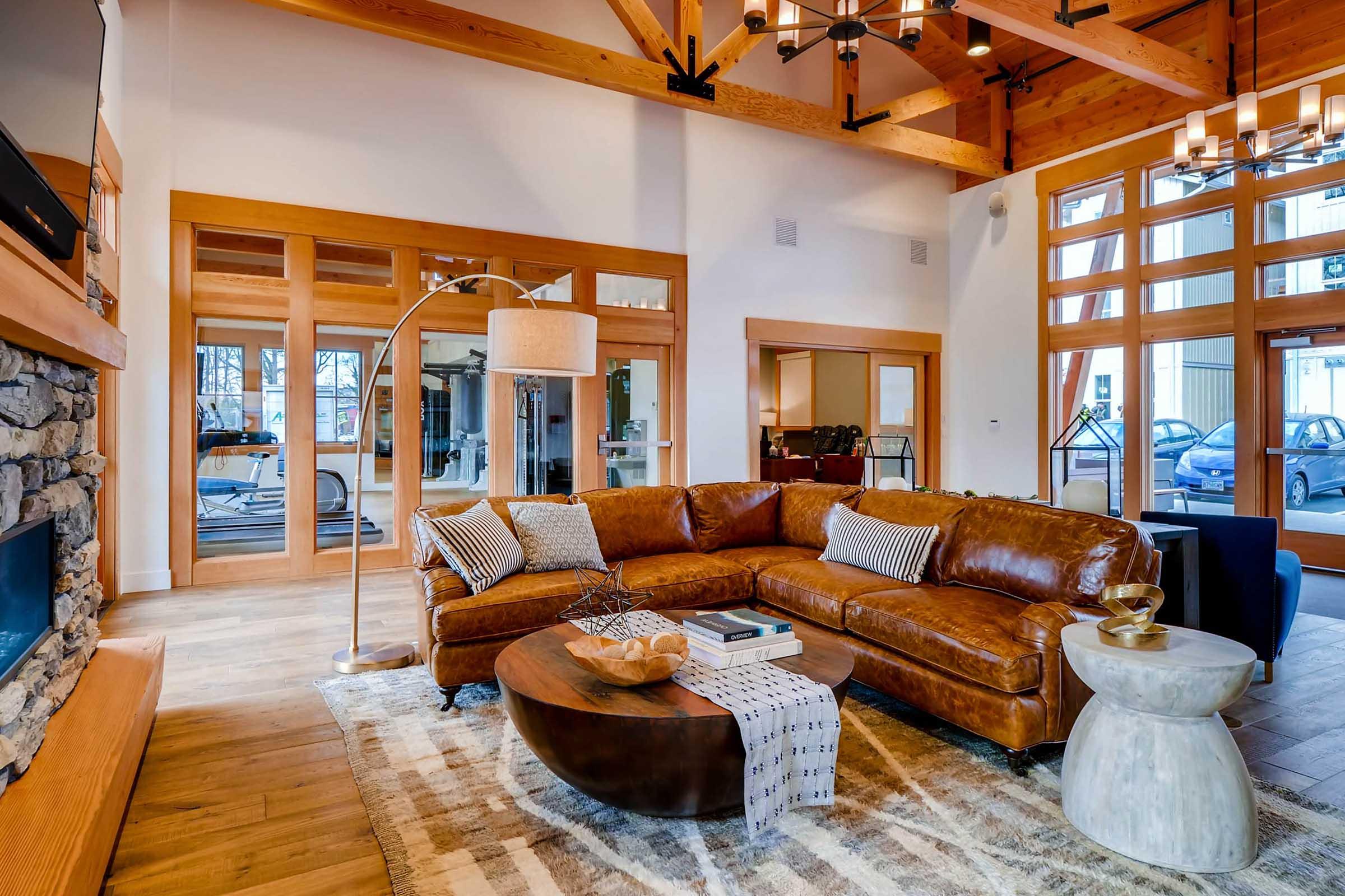 A cozy living room featuring a large brown leather sectional sofa, a round coffee table, and a stylish floor lamp.