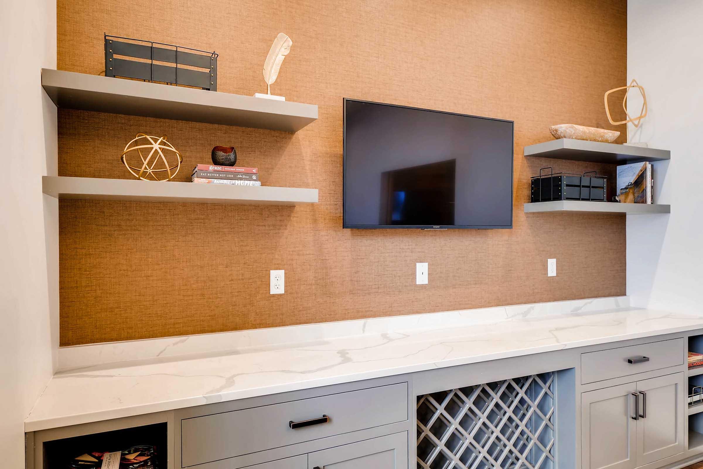 A modern entertainment center featuring a flat-screen TV mounted on a textured brown wall.
