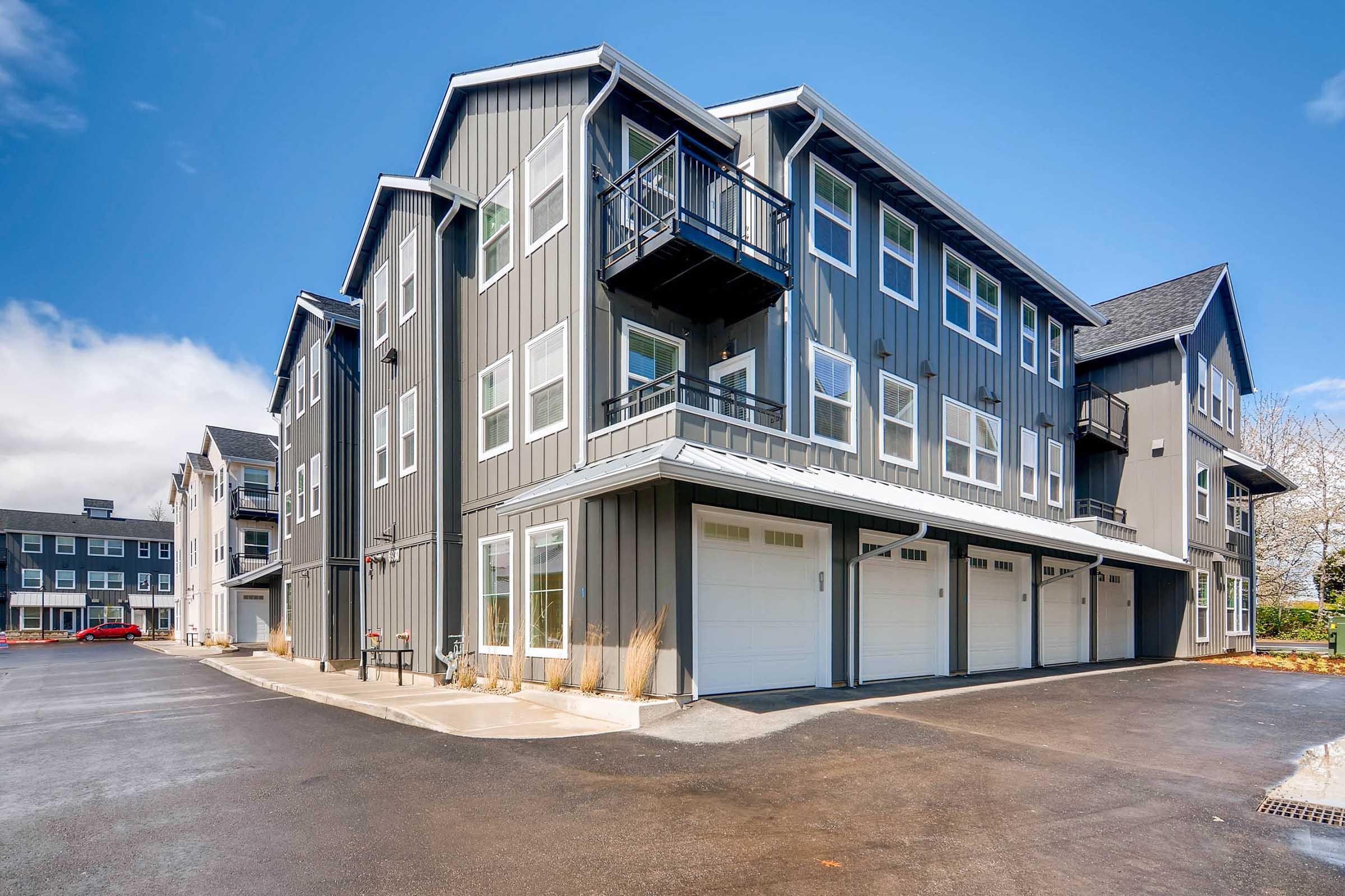 A modern multi-story building with a grey exterior, featuring large windows and balconies.