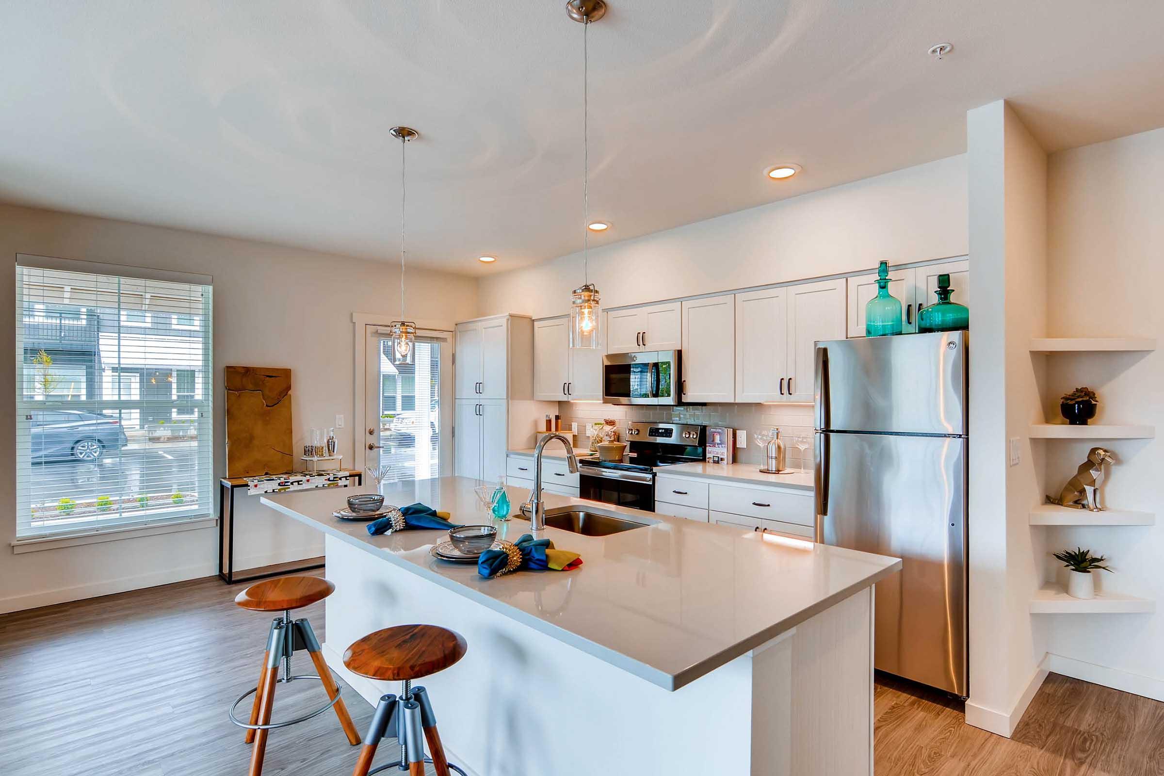 Modern kitchen featuring a spacious island with bar seating, stainless steel appliances, and light cabinetry.