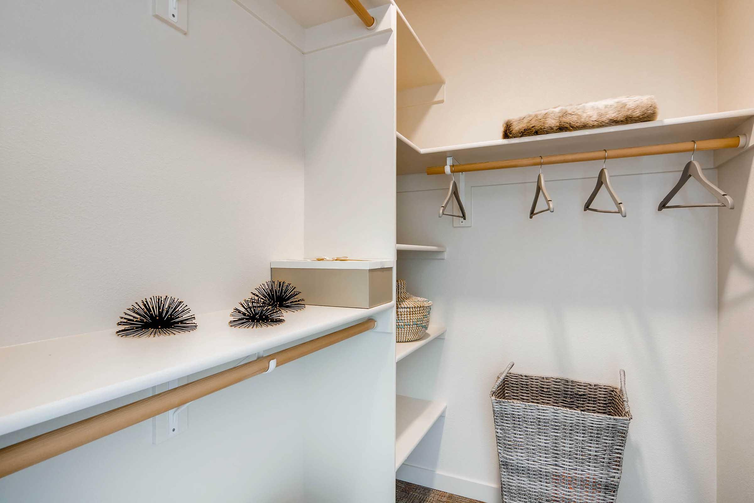 Organized closet space featuring a white shelf with decorative items, a storage box, and a woven basket.