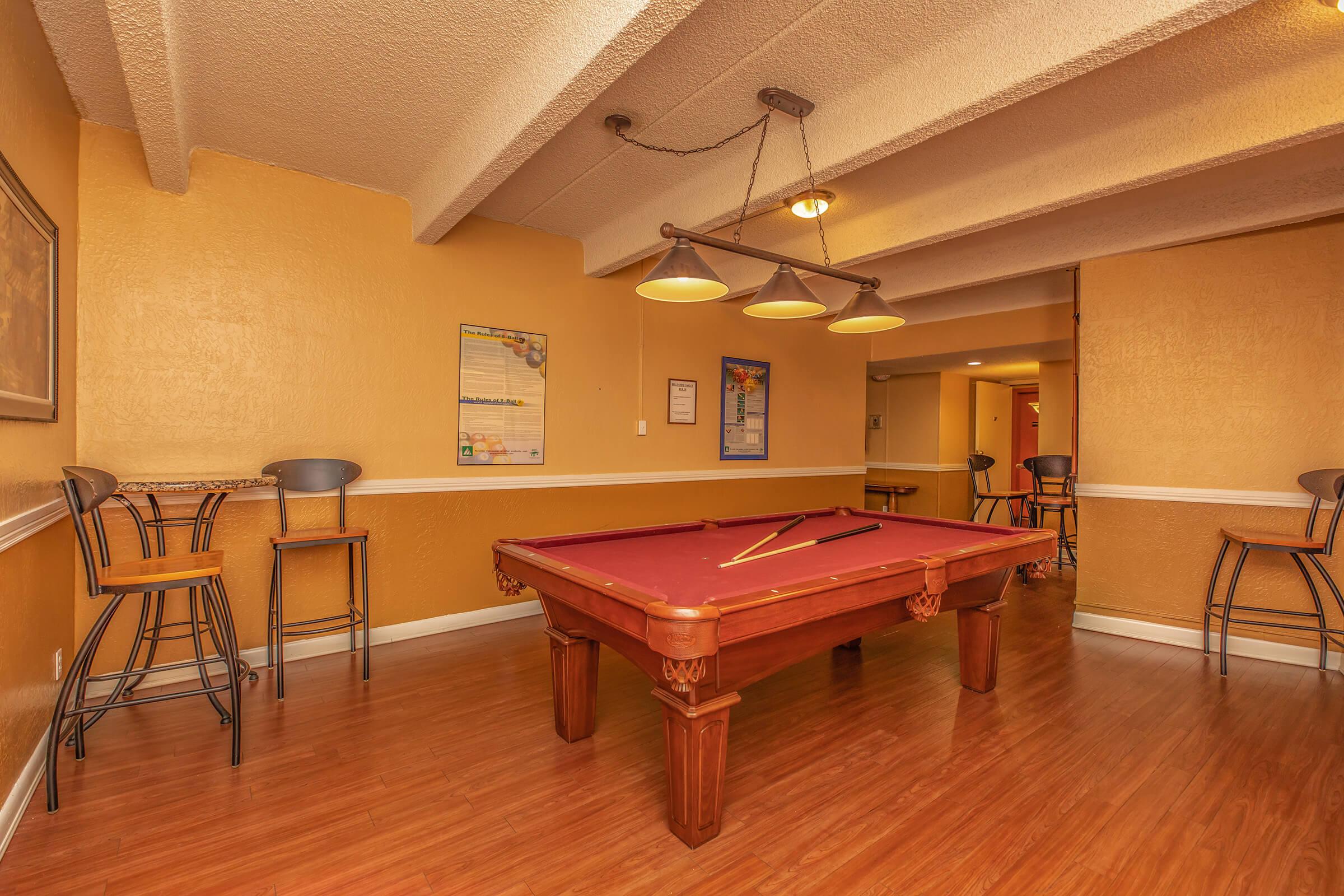 a pool table in the community room with wooden floors