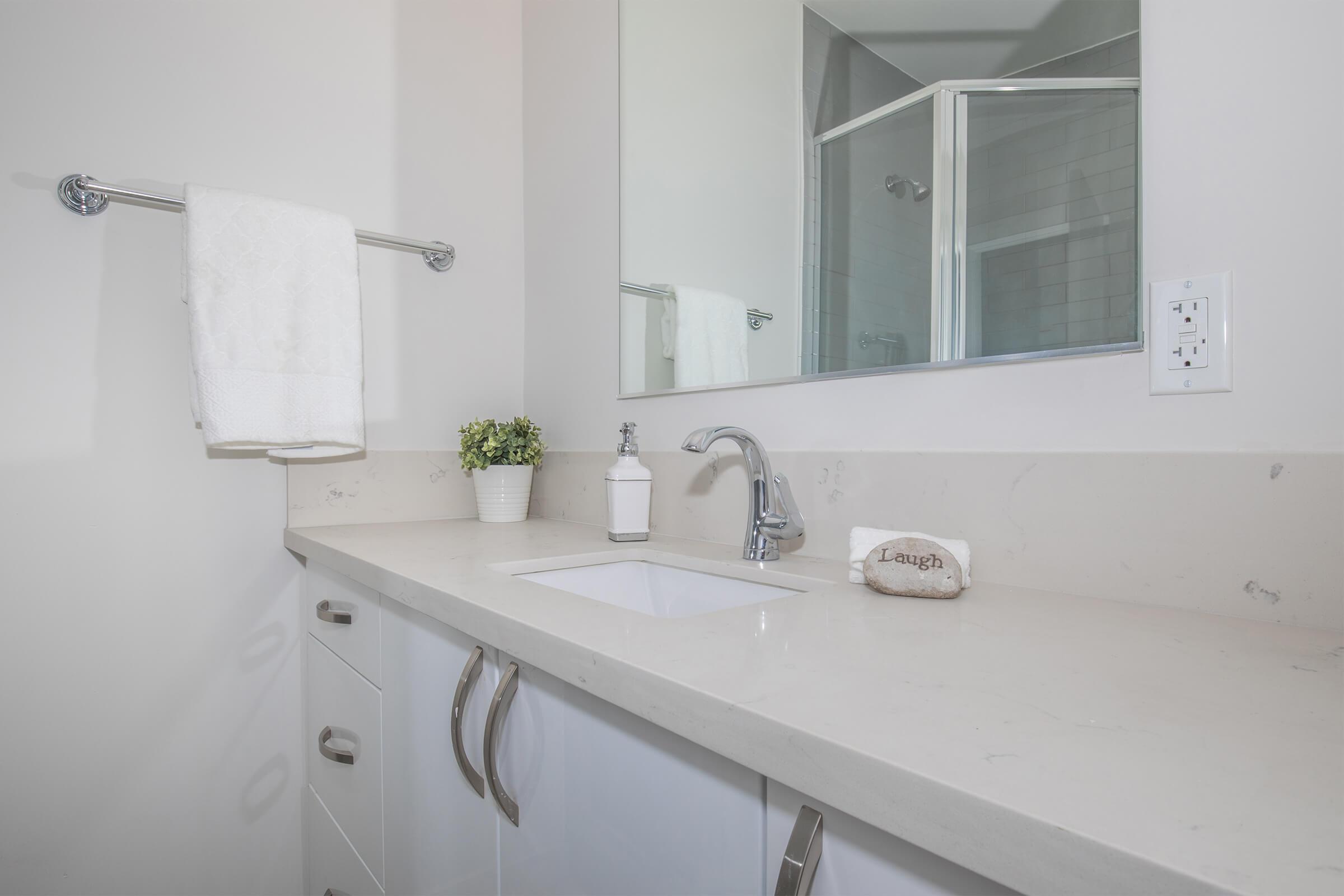 a white sink sitting under a mirror