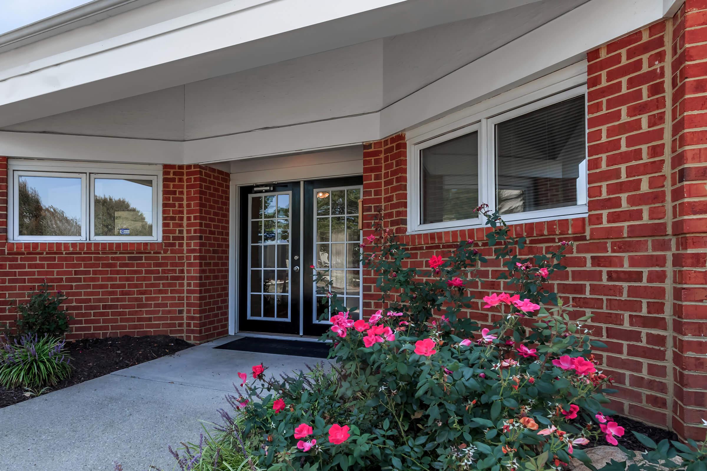 a close up of a flower garden in front of a brick building