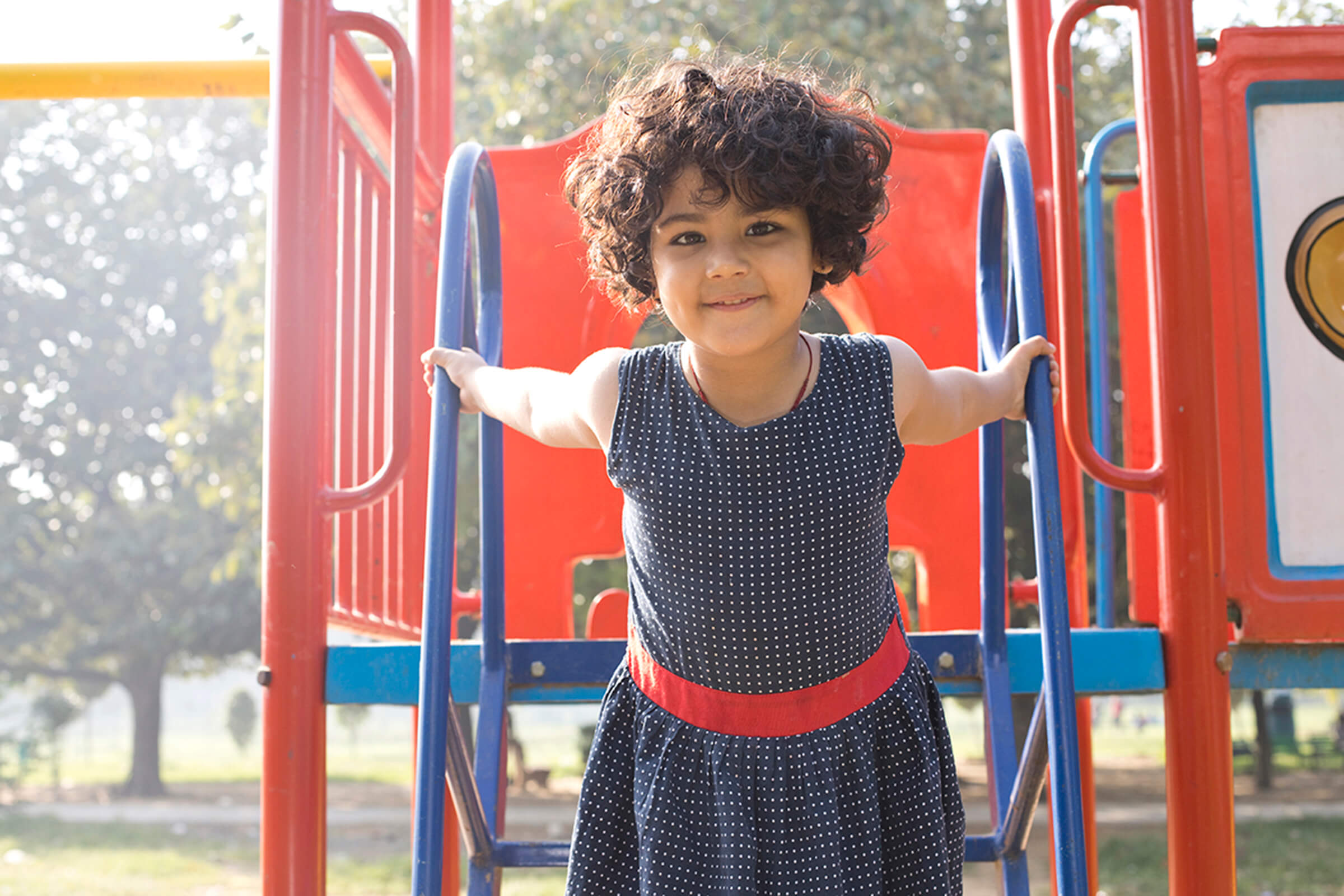 a young girl standing in front of a fence