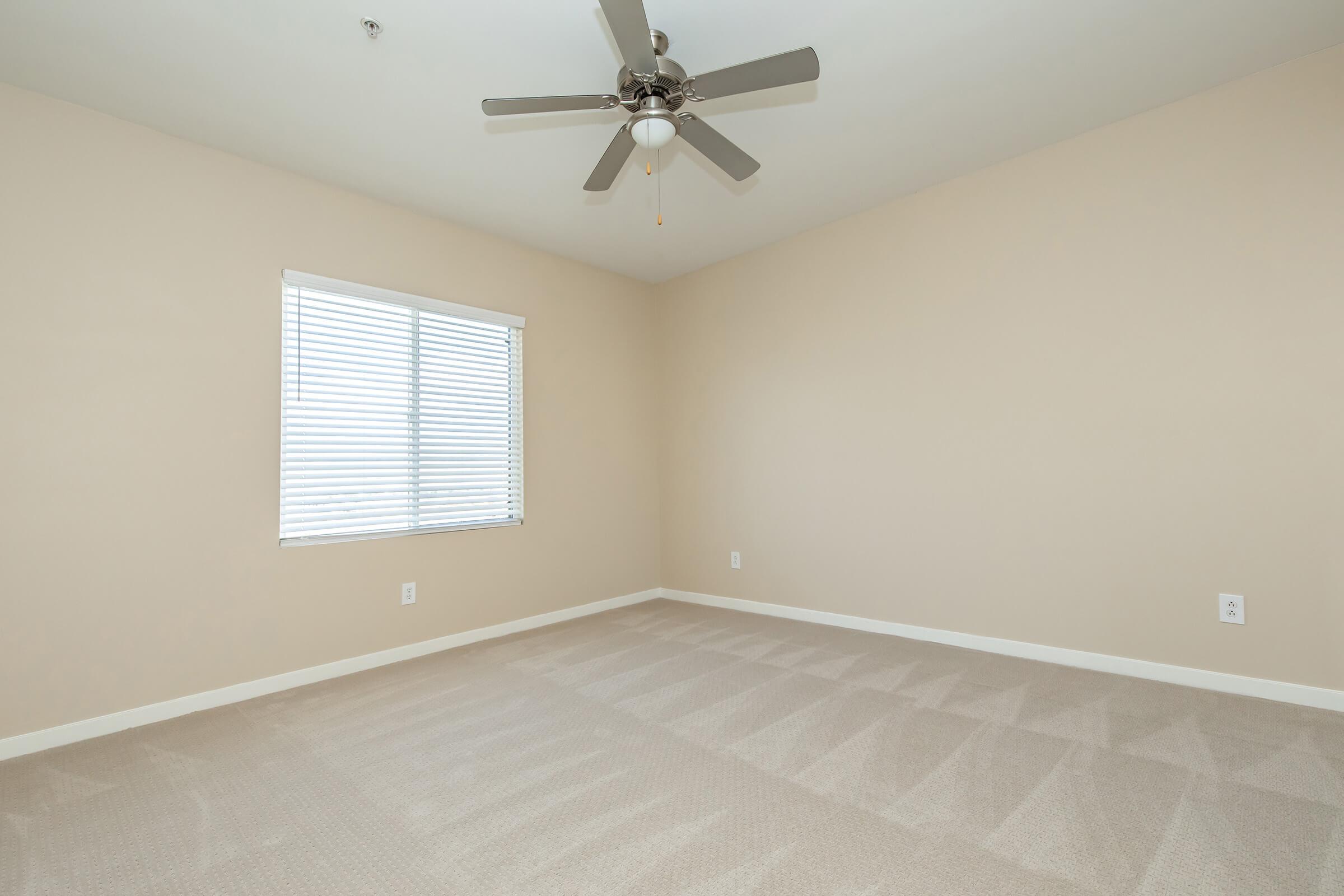 a vacant bedroom with a ceiling fan