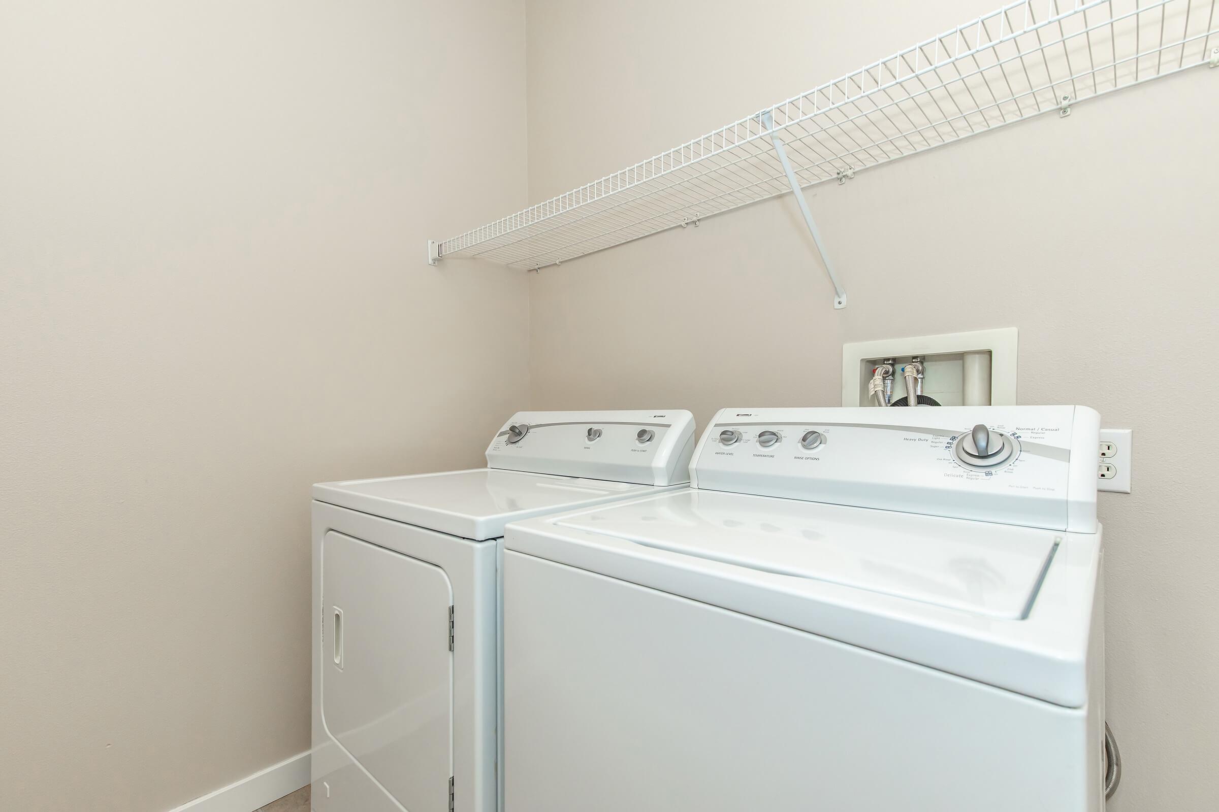 a washer and dryer in the laundry closet with a shelf