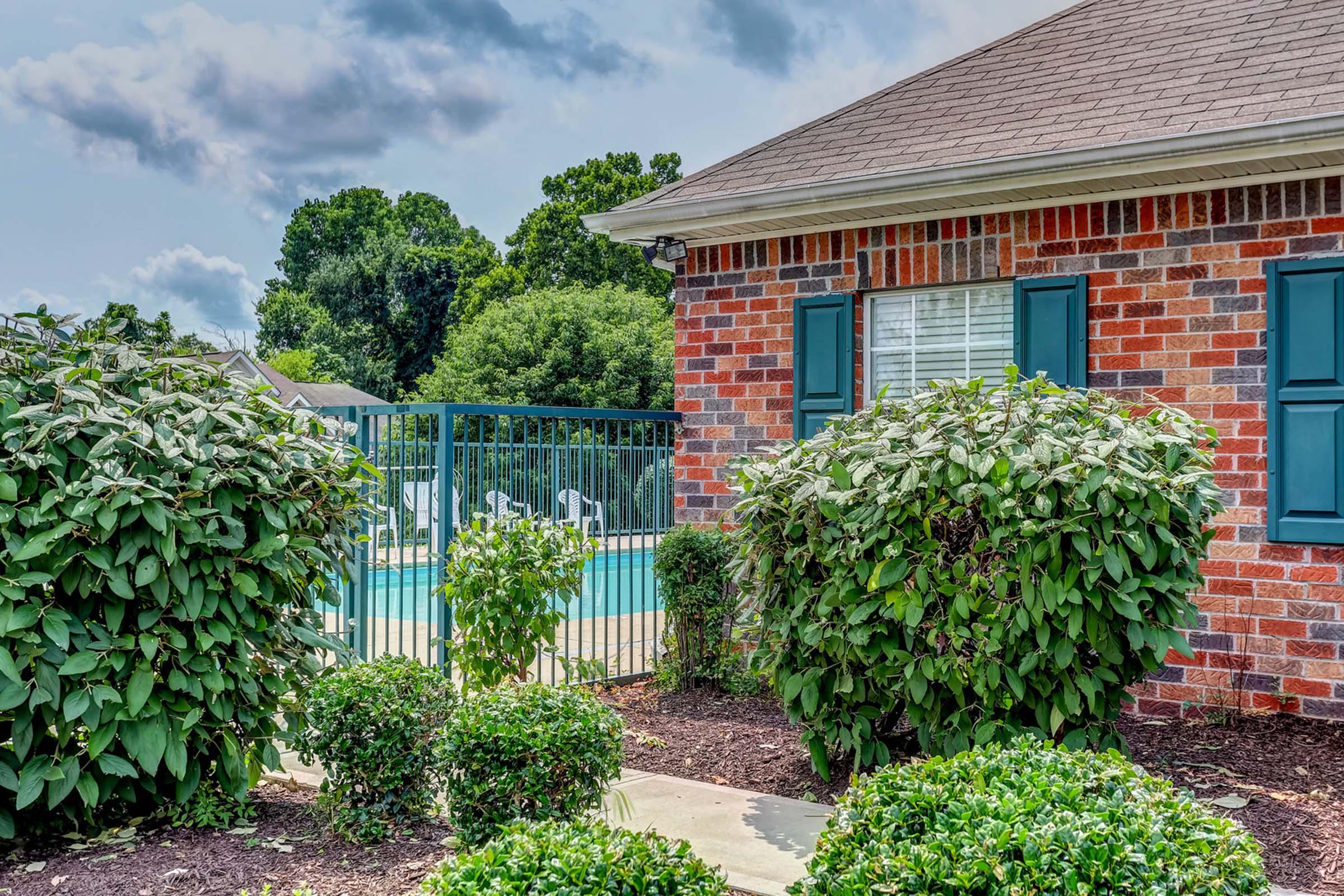 a house with bushes in front of a brick building