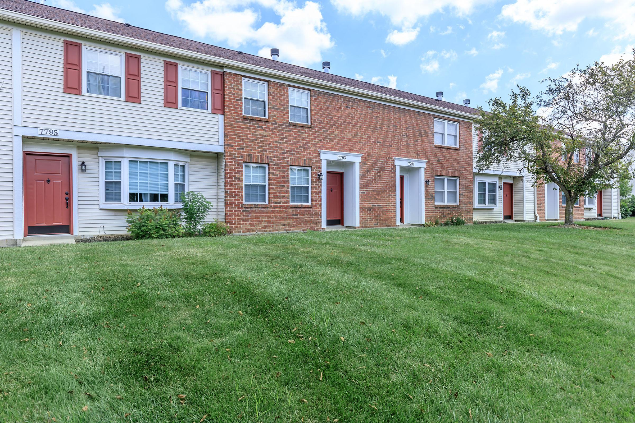 a large brick building with grass in front of a house