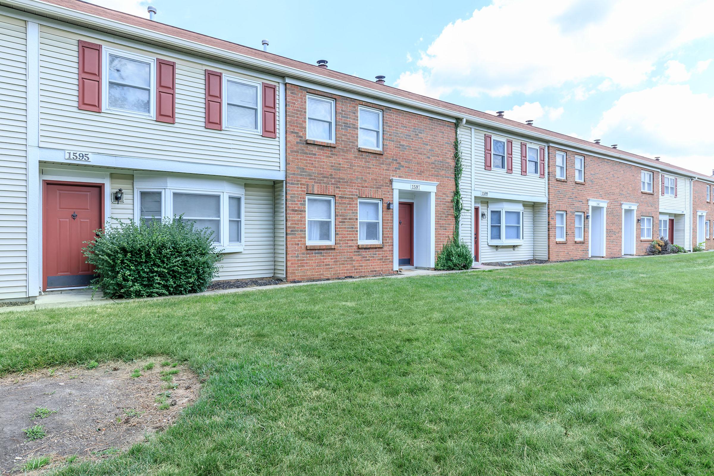 a large brick building with grass in front of a house