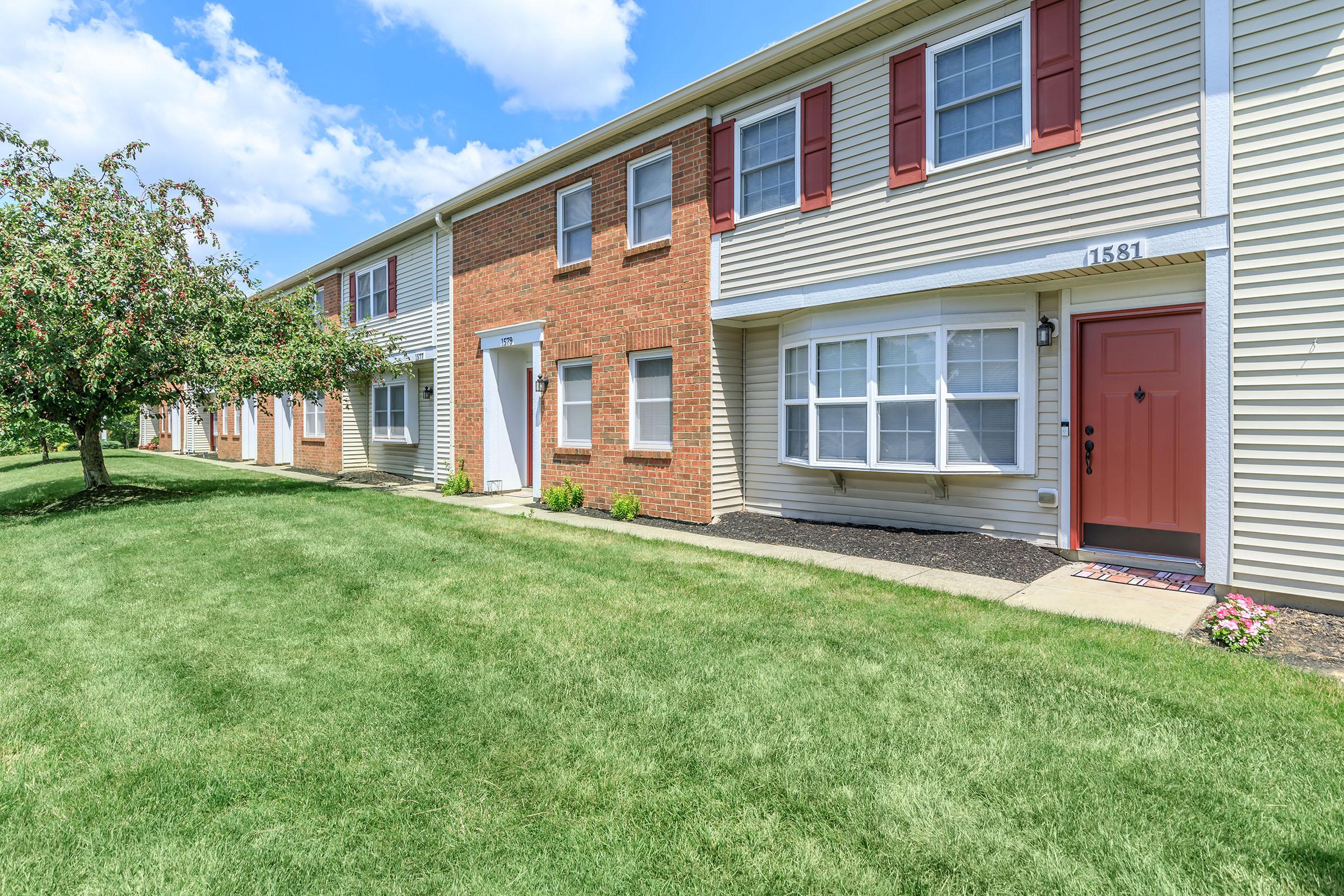 a large brick building with grass in front of a house