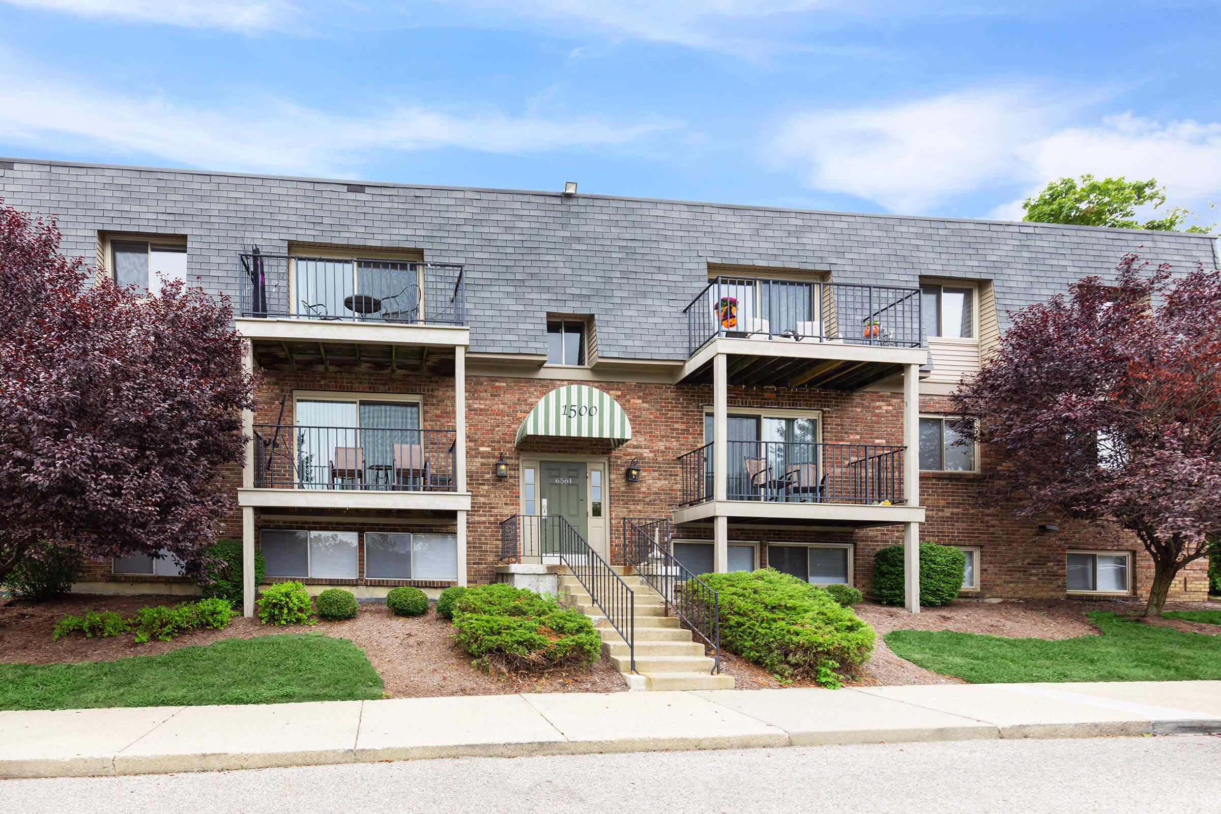 a house with bushes in front of a brick building