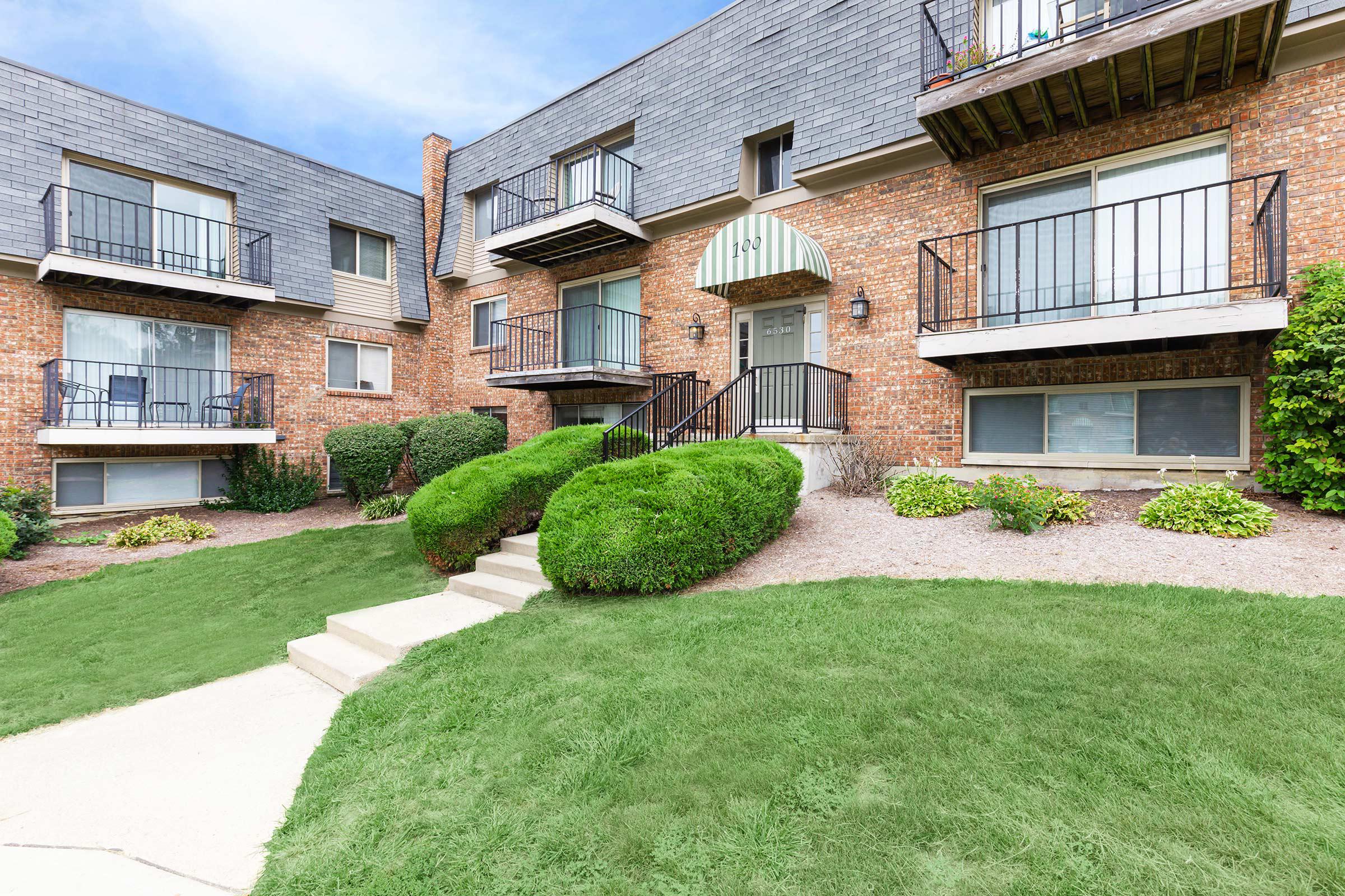 a large brick building with grass in front of a house