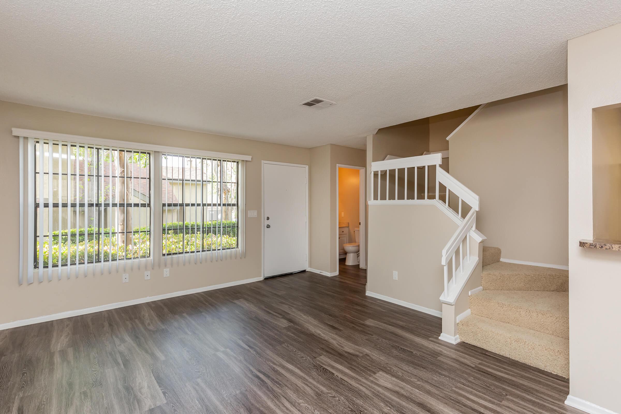 Living room with wooden floors and carpeted stairs