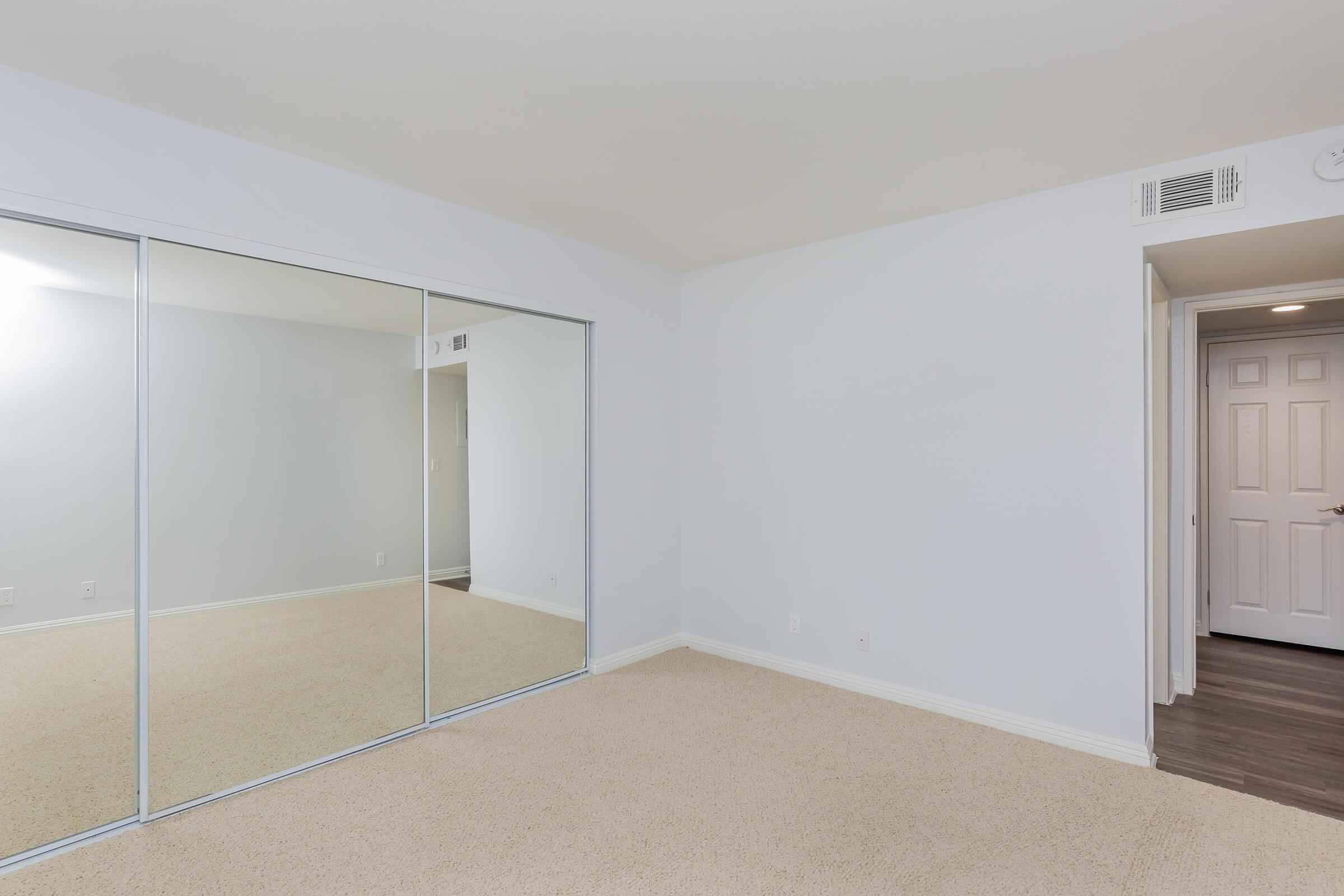 Carpeted bedroom with mirror glass sliding closet doors