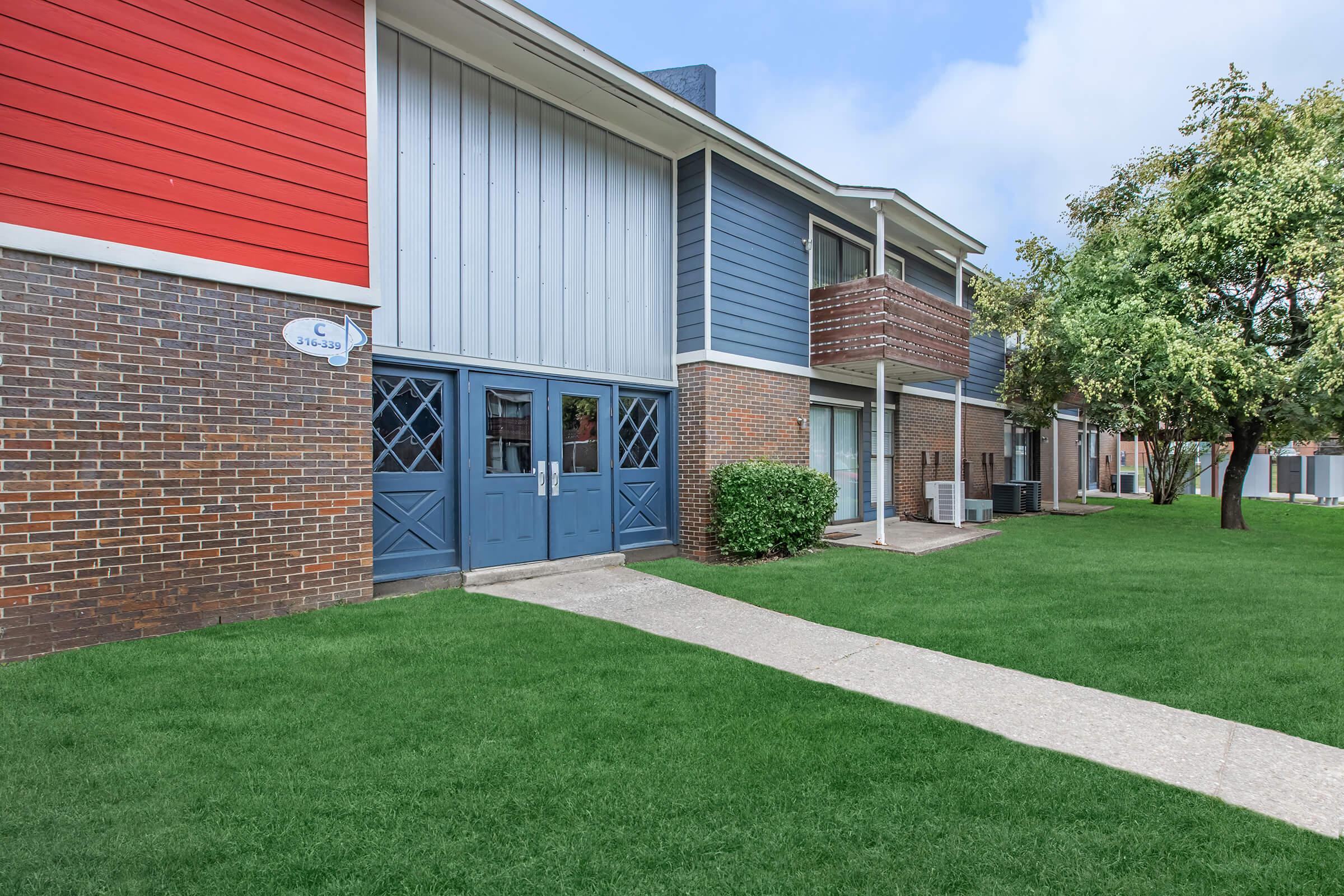 a house with a lawn in front of a brick building