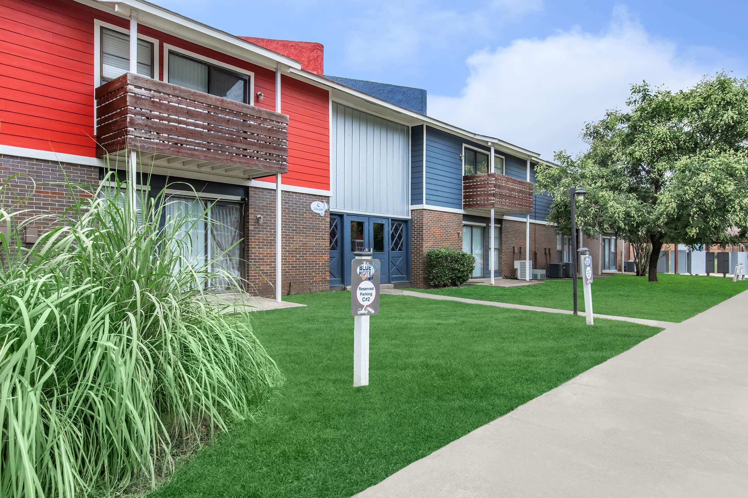 a house with a lawn in front of a brick building